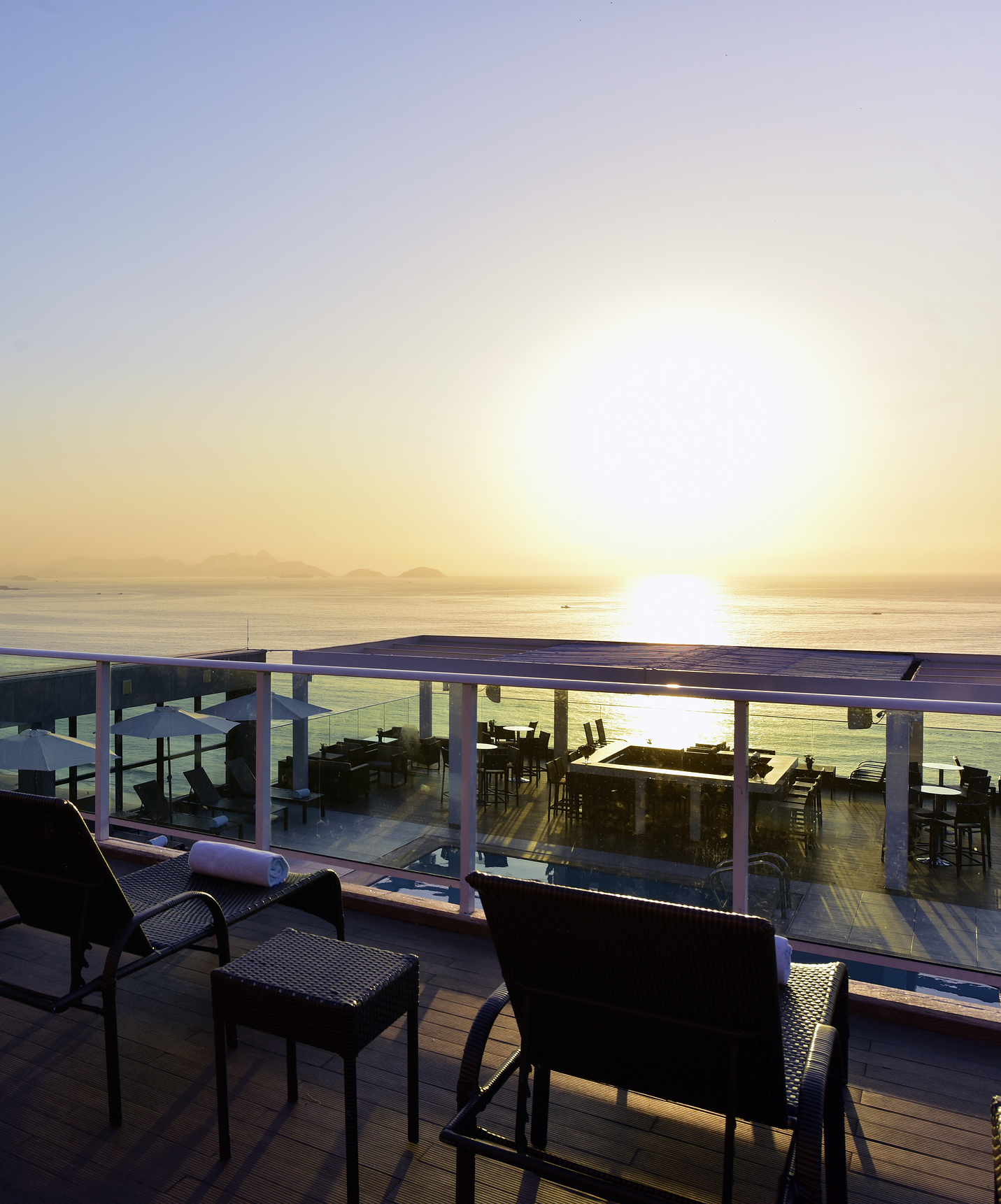 Dachterrasse des Hotels am Strand von Copacabana mit Liegen und Blick auf das Meer und die Berge während des Sonnenuntergangs