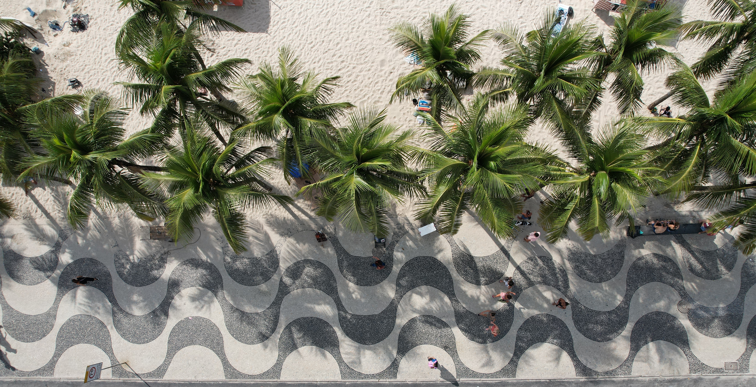 Menschen, die auf dem schwarz-weißen gewellten Gehweg von Copacabana spazieren, ein Wahrzeichen von Rio de Janeiro