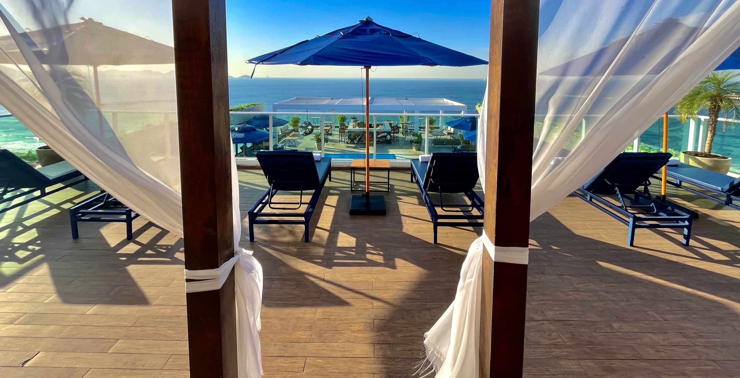 Blick auf das Meer von der Dachterrasse im Hotel am Strand von Copacabana mit Liegen, Sonnenschirmen und einem Pool