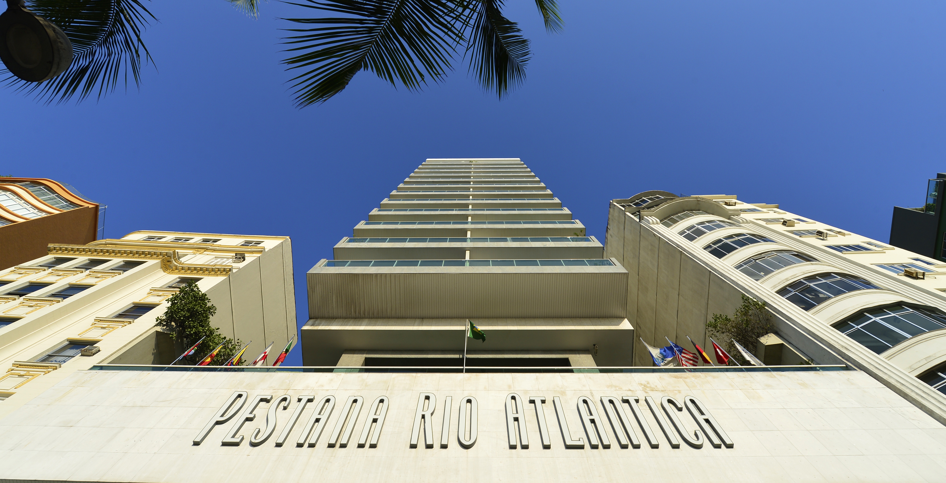 Gebäude des Pestana Rio Atlântica mit mehreren Zimmern mit Balkon und mehreren Fahnen über dem Hotelnamen