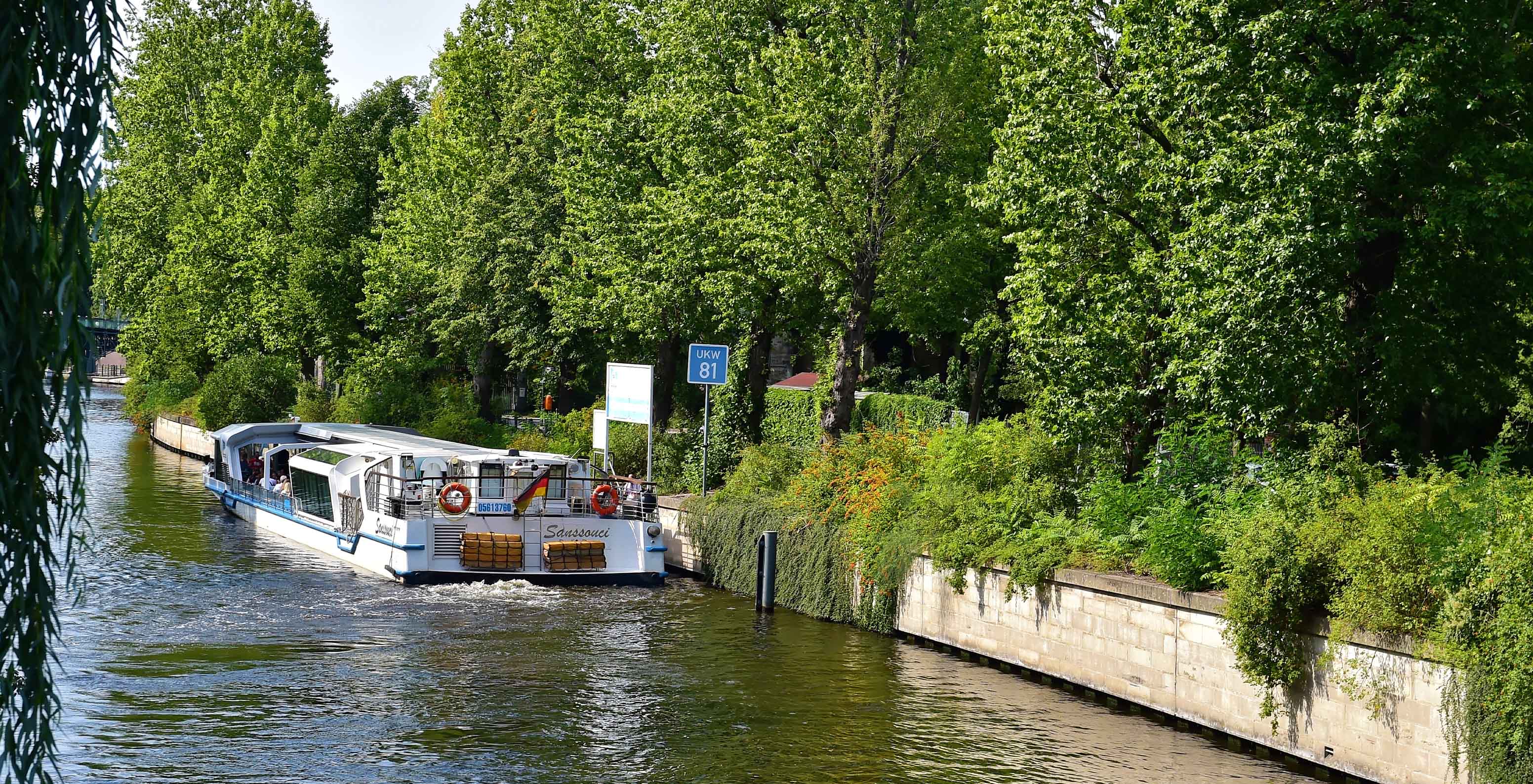 Fluss in Berlin, mit einem großen Boot, auf dem man Fahrten unternehmen kann