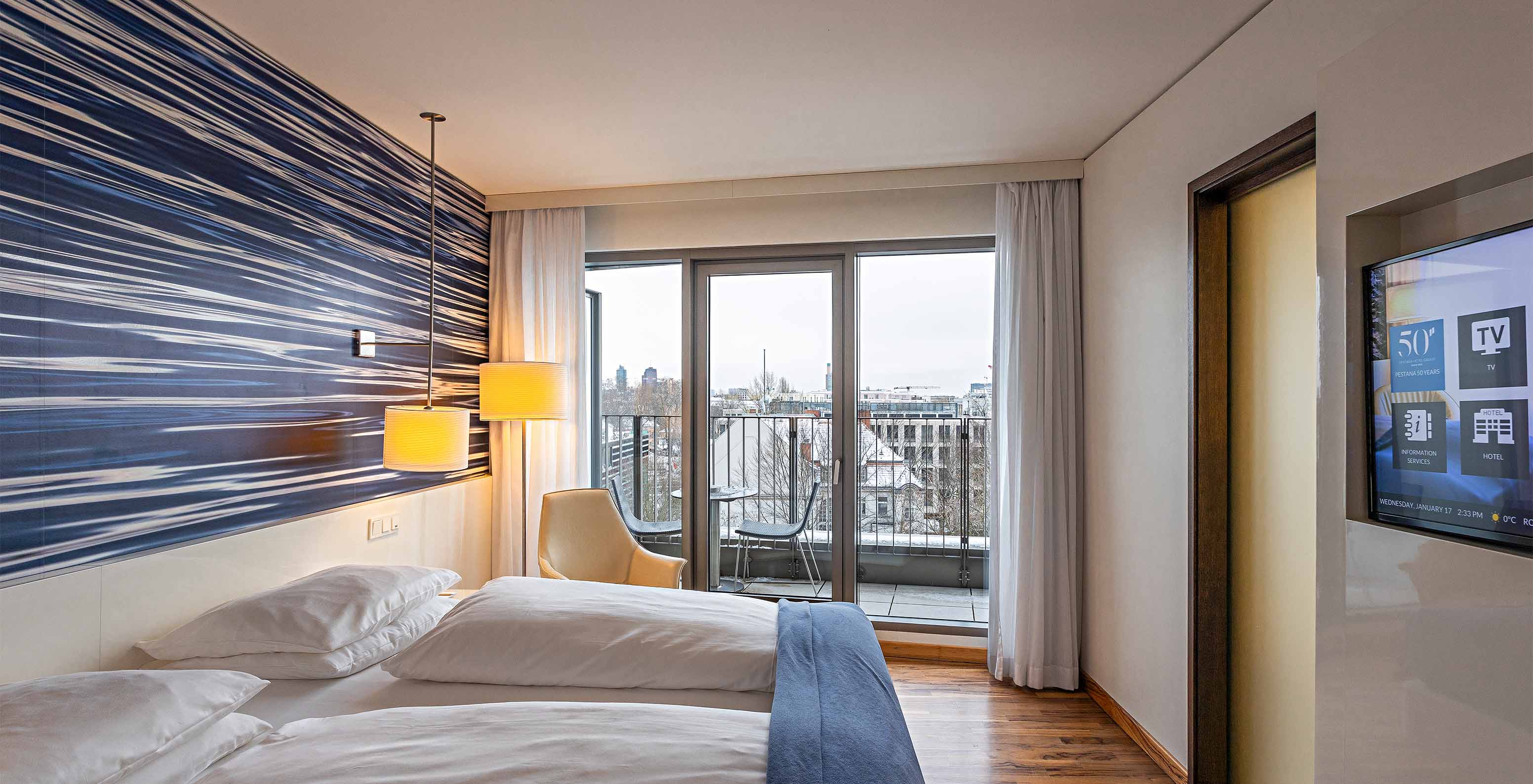 Das Premium Zimmer mit Balkon im Pestana Berlin Tiergarten hat einen Fernseher, Balkon mit Stadtblick und einen Sessel