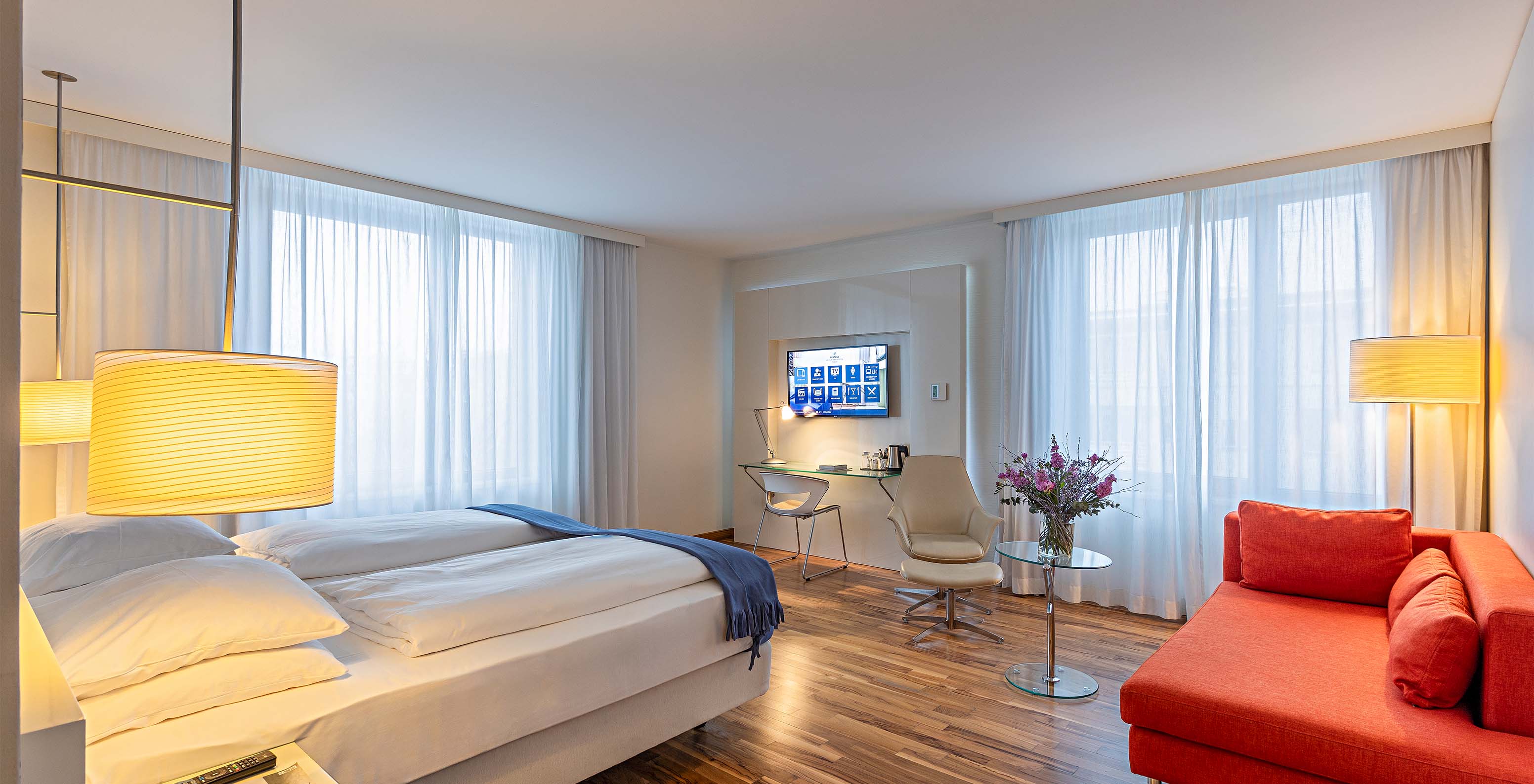 Das Grand Deluxe Zimmer im Pestana Berlin Tiergarten hat ein Doppelbett, Fernseher, Sofa, Sessel und Schreibtisch