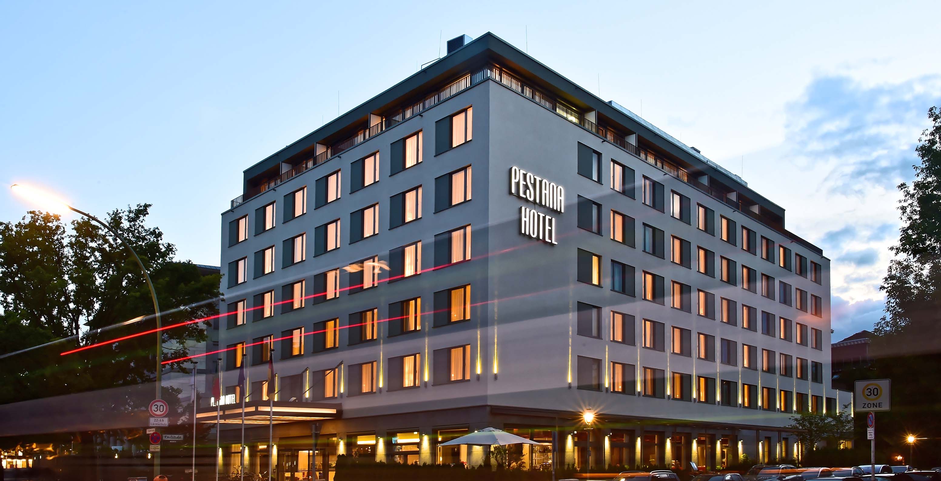 Nächtliche Außenansicht des Pestana Berlin, ein 4-Sterne-Hotel im Zentrum, beleuchtet von den Lichtern der Hotelfassade