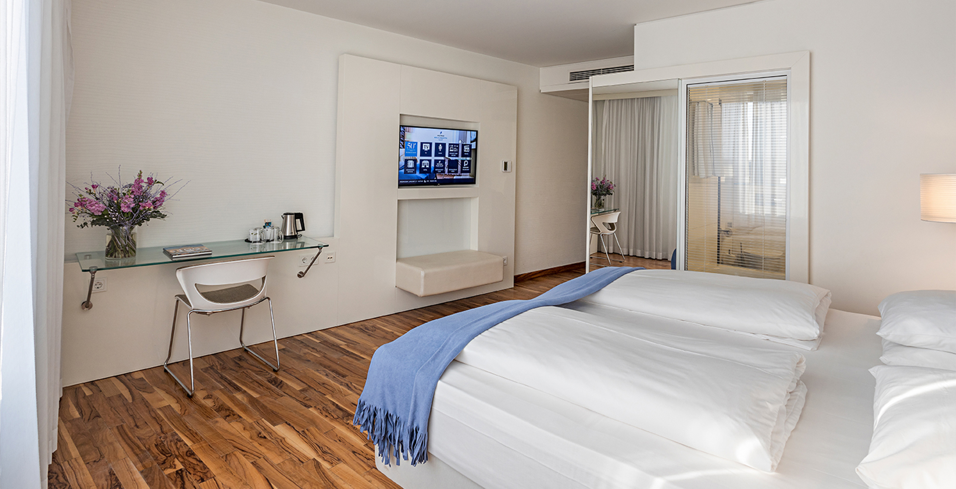 Das Deluxe Zimmer im Pestana Berlin Tiergarten hat einen Fernseher, einen Schreibtisch mit Lampe und Stuhl, Sofa und Sessel