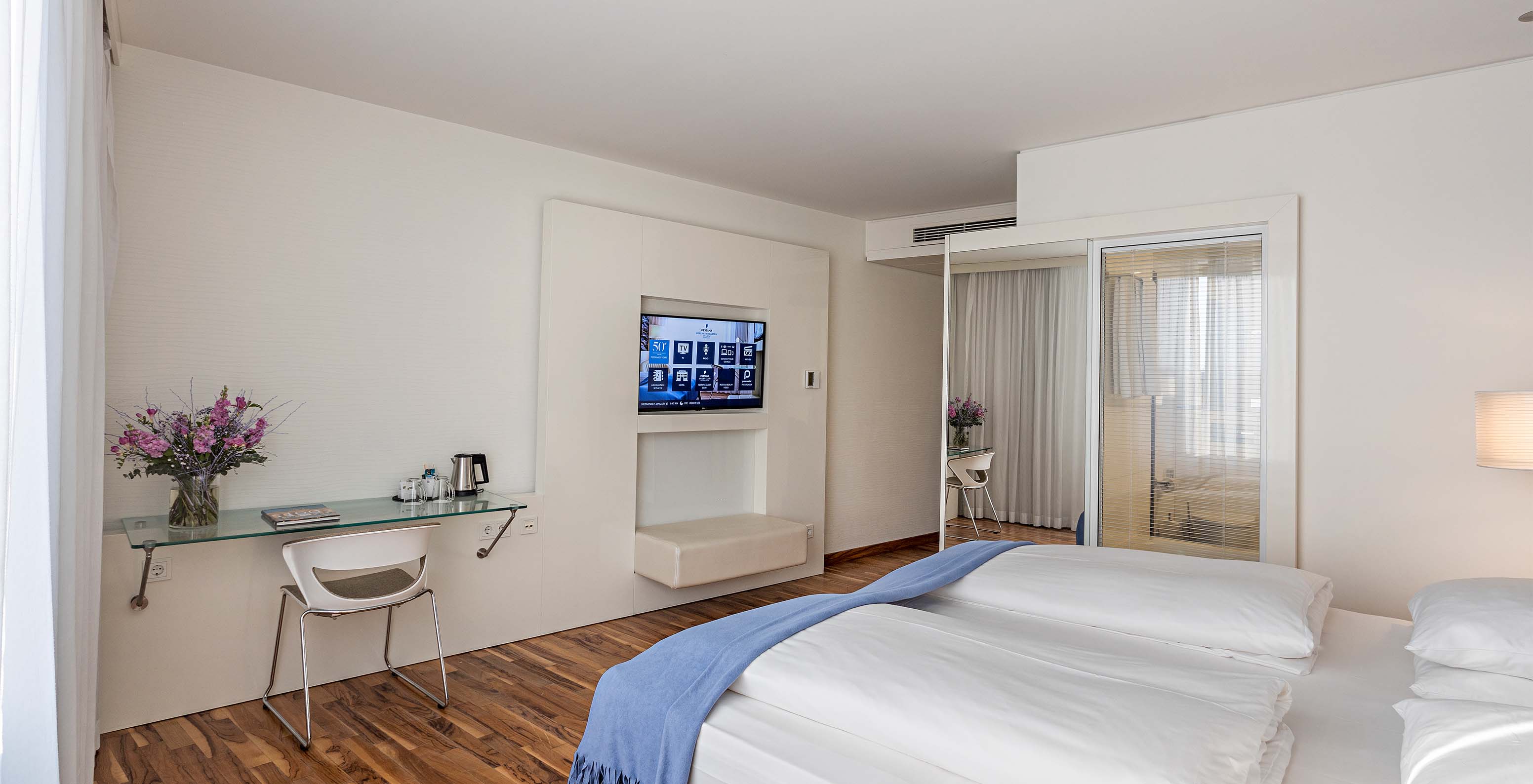 Das Deluxe Zimmer im Obergeschoss im Pestana Berlin Tiergarten hat ein Doppelbett, einen Schreibtisch und einen Fernseher