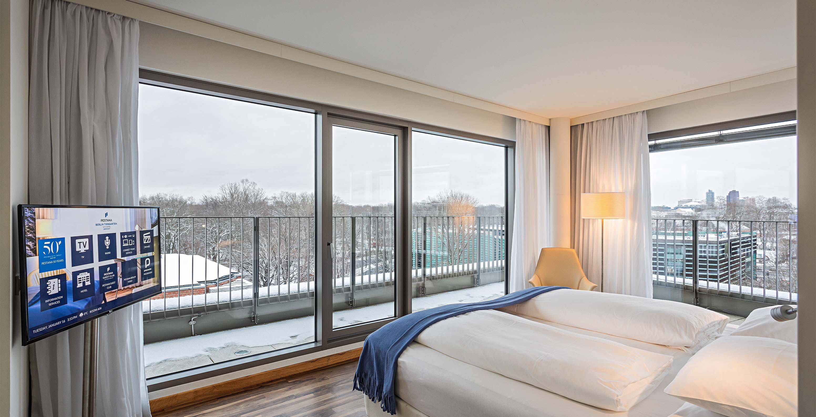 Die Panoramasuite im Pestana Berlin Tiergarten hat ein Doppelbett, Fernseher und einen Balkon mit Stadtblick