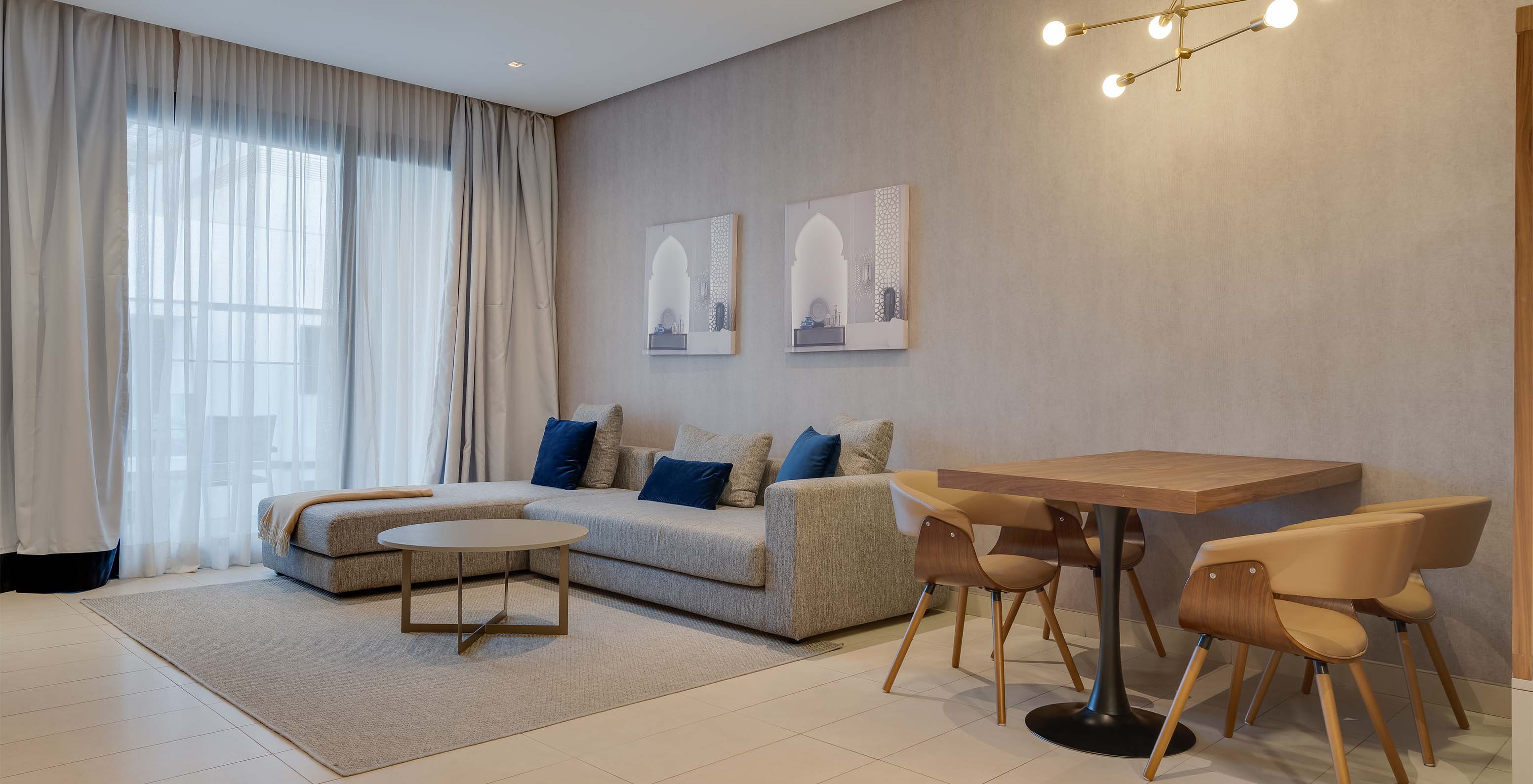 Die Familien-Premium-Suite im Pestana Casablanca hat ein großes graues Sofa mit Chaiselongue neben dem Fenster