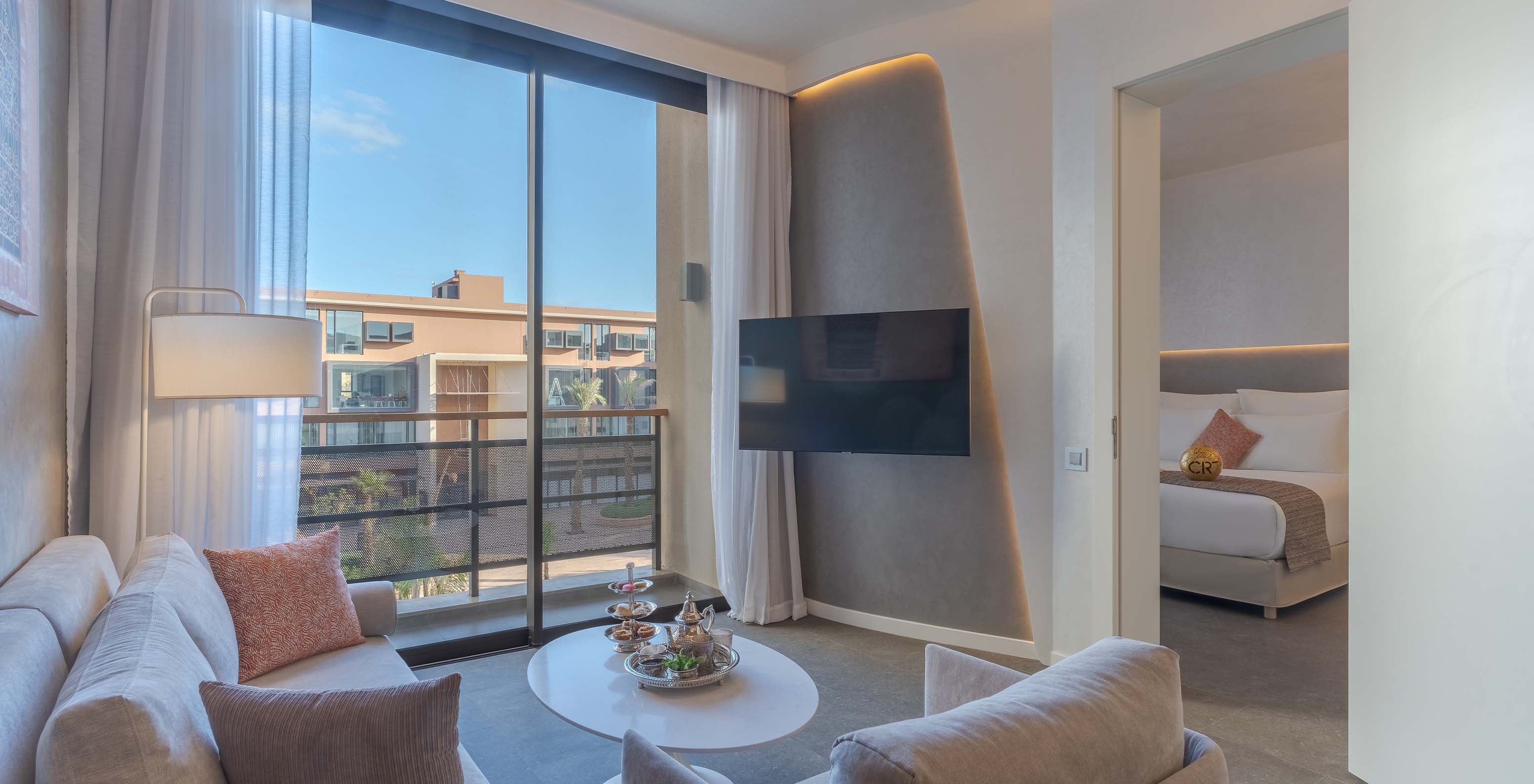 Die CR7 Suite Avenue im Pestana CR7 Marrakeck hat ein Wohnzimmer mit Sofas, Fernseher und Balkon mit Blick auf die M Avenue