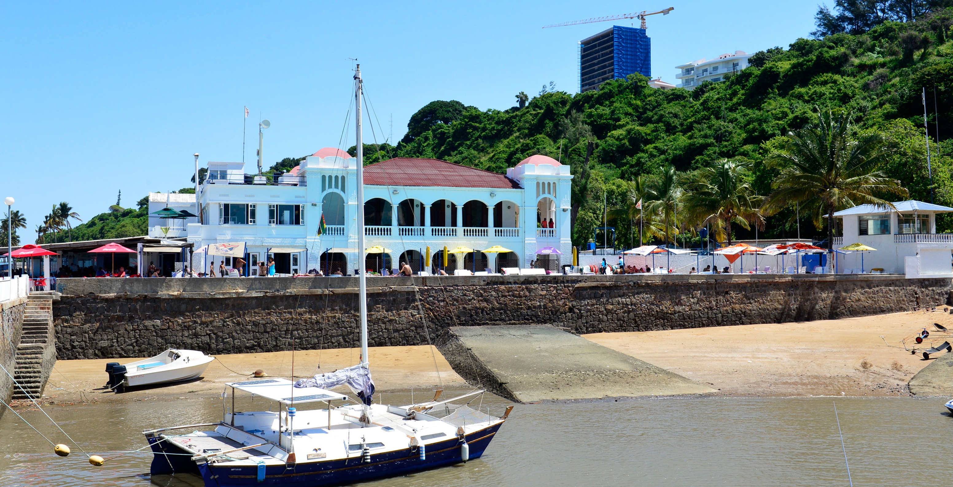 Hafen von Maputo, lebhaft und geschäftig, mit kleinen Booten im Wasser und der Stadt Maputo im Hintergrund