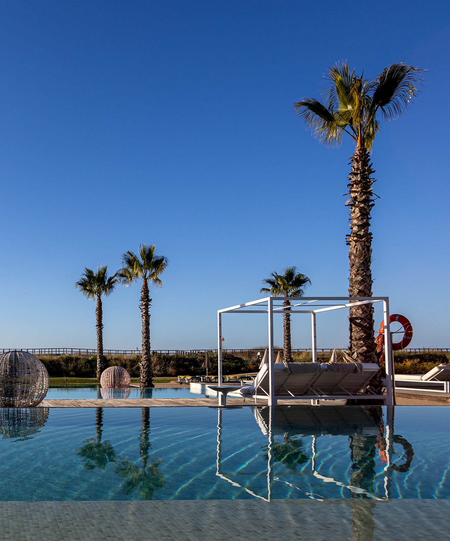 Das Pestana Alvor South Beach hat 3 Infinity-Pools, umgeben von Palmen und Liegen, die perfekte Kulisse zum Entspannen