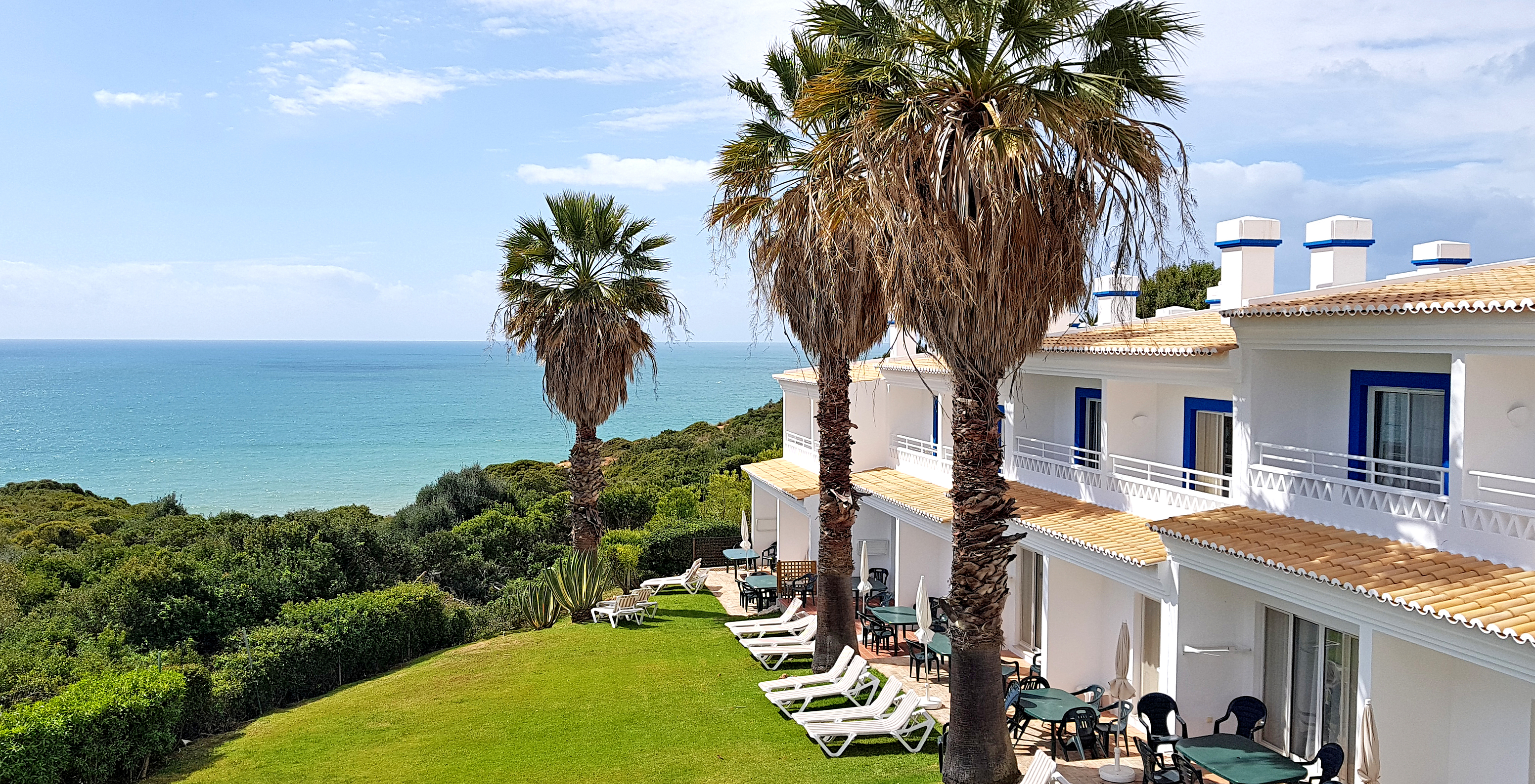 Villen im Pestana Palm Gardens in Carvoeiro, mit Garten und Palmen davor und Blick auf das Meer und den Horizont