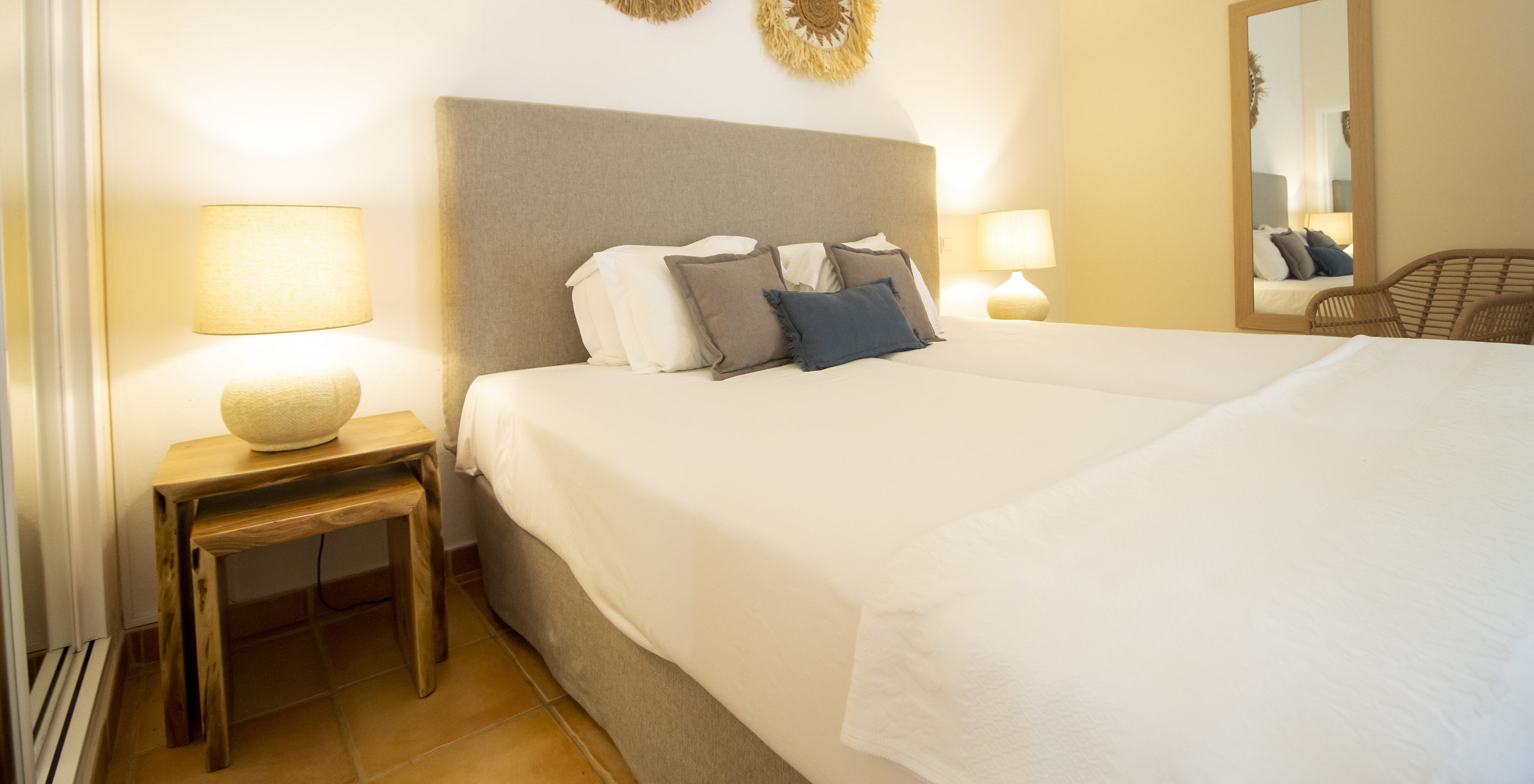 Das T2 Standard Appartement im Pestana Palm Gardens hat ein Doppelbett mit dekorativen Kissen und Bildern