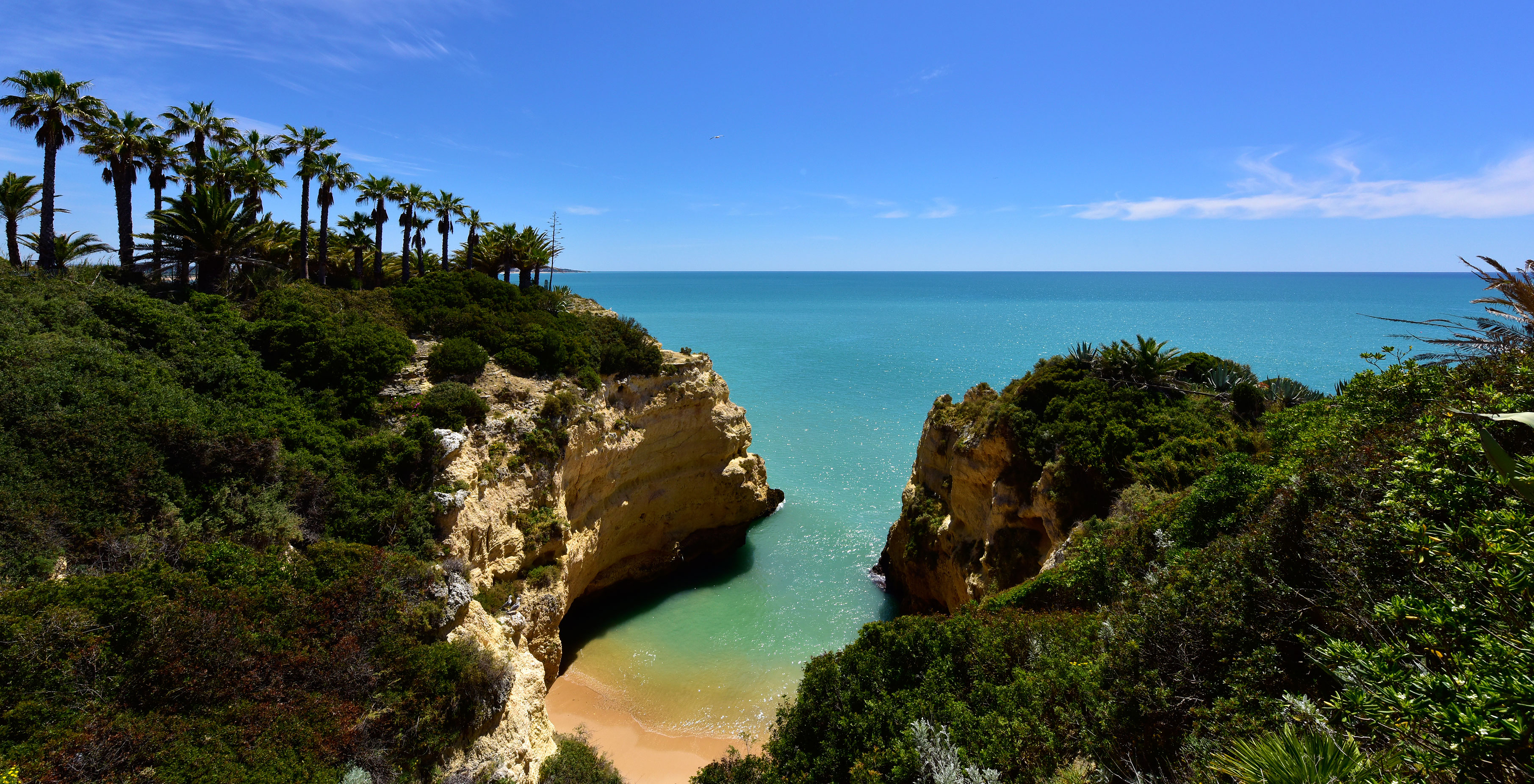 Blick auf das Pestana Viking, vom Strand der Escaleiras aus, mit klarem blauen Meer, umgeben von Klippen und Vegetation