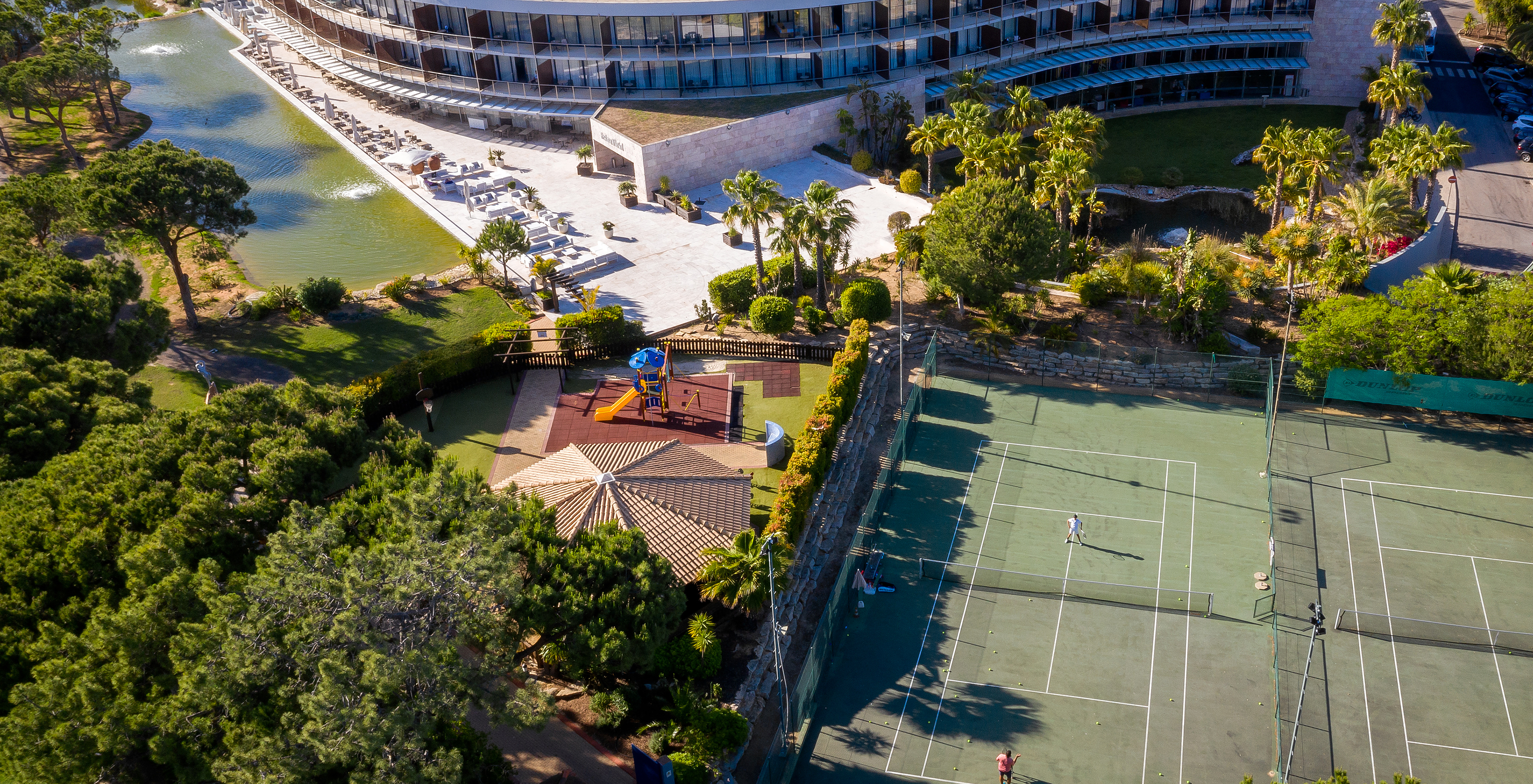 Blick auf das Pestana Vila Sol - Vilamoura bei Sonnenuntergang, mit einer Terrasse, einem See, Außenpool und Tennisplatz