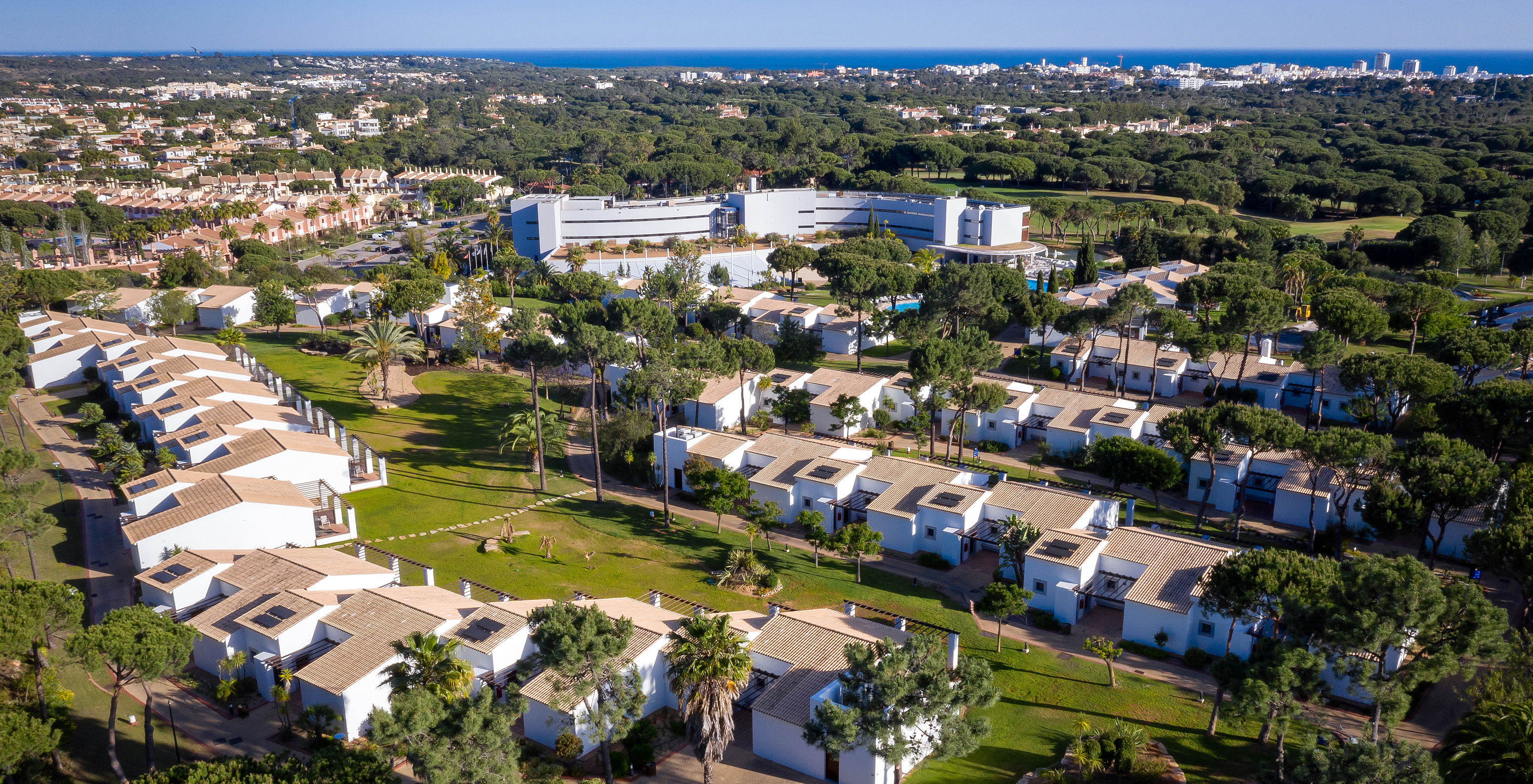 Zimmer im Pestana Vila Sol mit Balkon, umgeben von Vegetation und dem Hauptgebäude