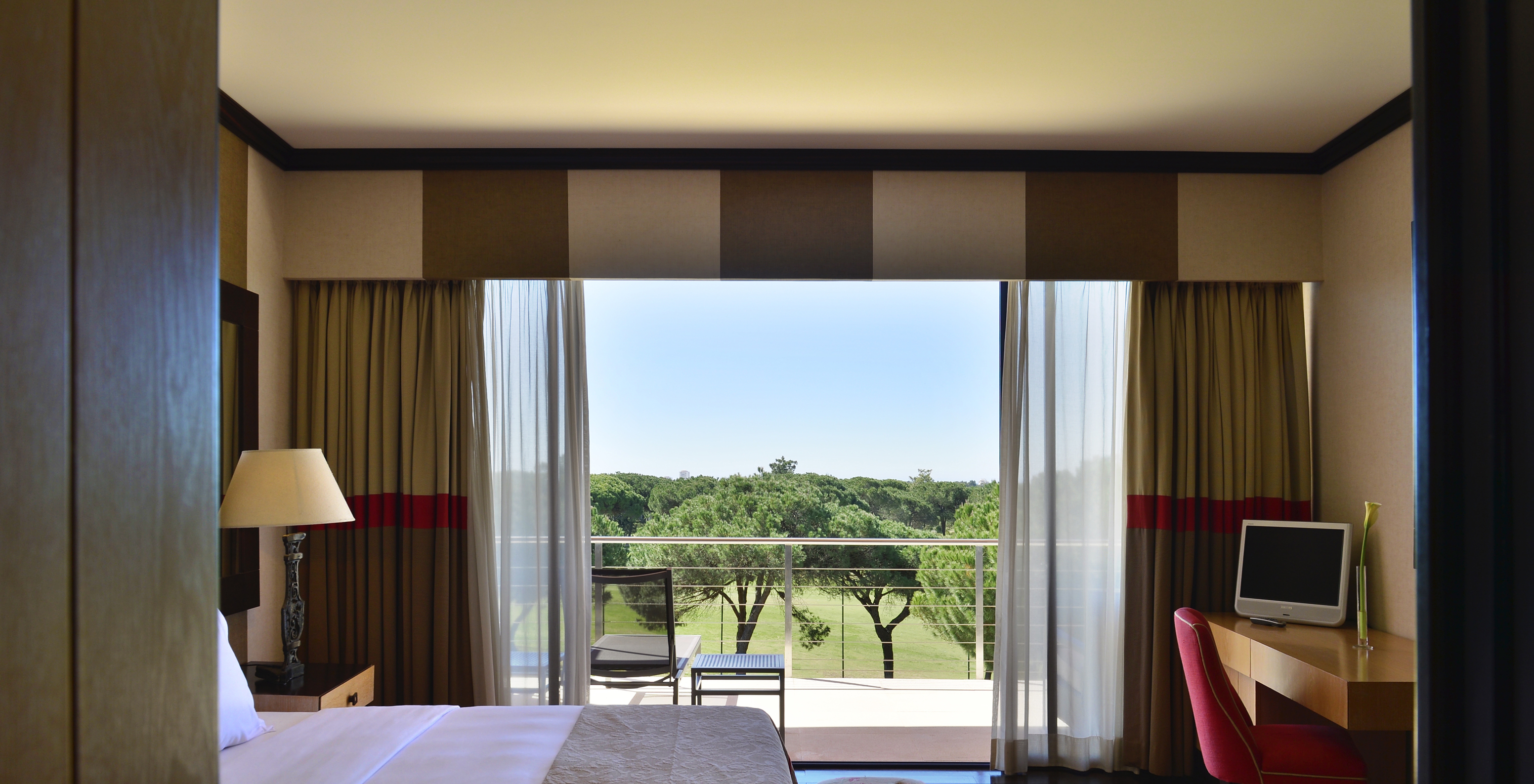 Präsidentensuite Pestana Vila Sol - Vilamoura hat ein Bett, Schreibtisch und einen Balkon mit Blick auf den Garten