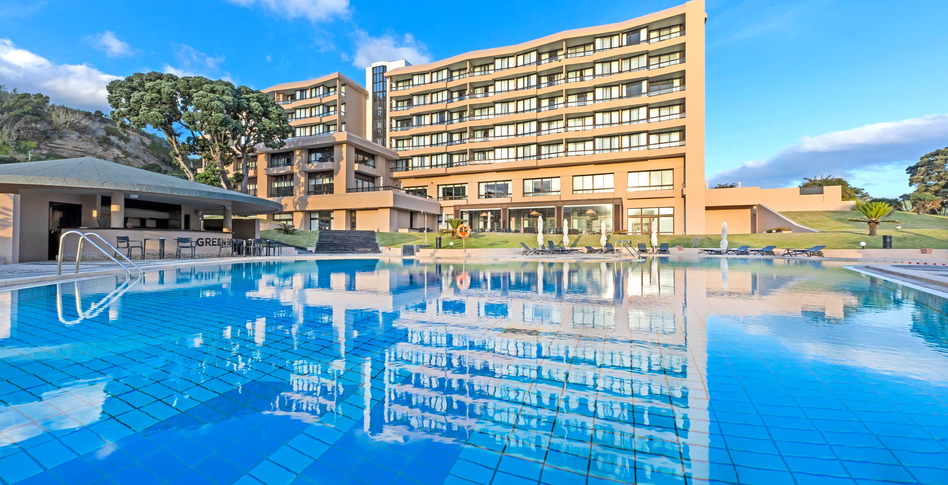 Außenschwimmbad im 4-Sterne-Hotel auf der Insel São Miguel mit Blick auf Liegen und das Hauptgebäude