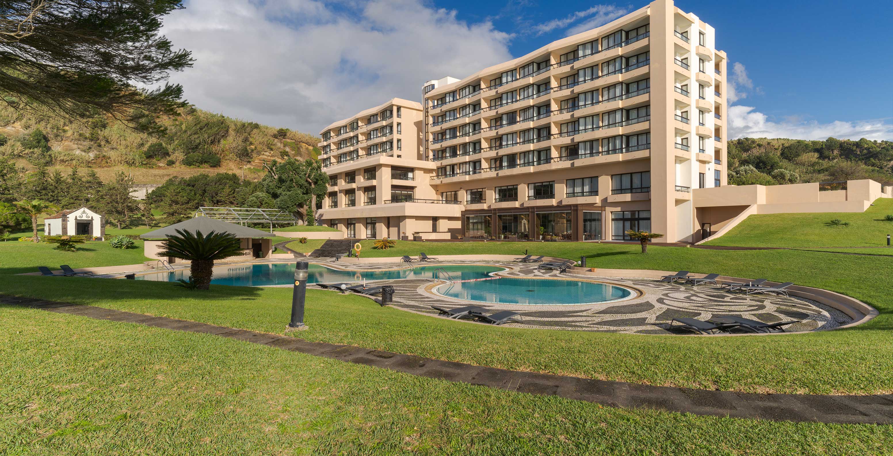 Blick auf den Außenpool des Pestana Bahia Praia, mit dem Hotelgebäude im Hintergrund, Zimmer mit Balkonen