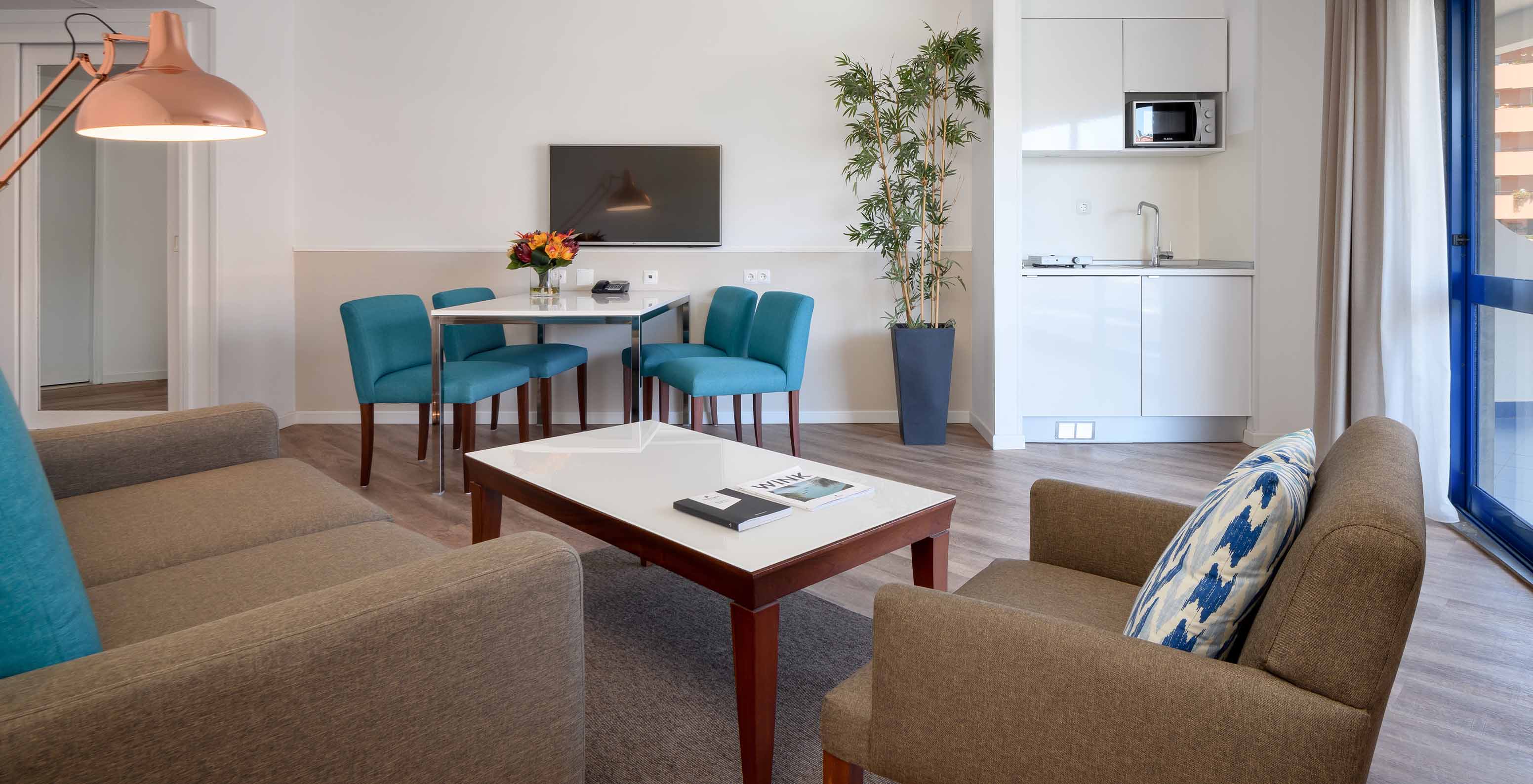 Die Deluxe Suite im Pestana Cascais hat ein Wohnzimmer mit Sofa, Couchtisch, Essbereich und TV