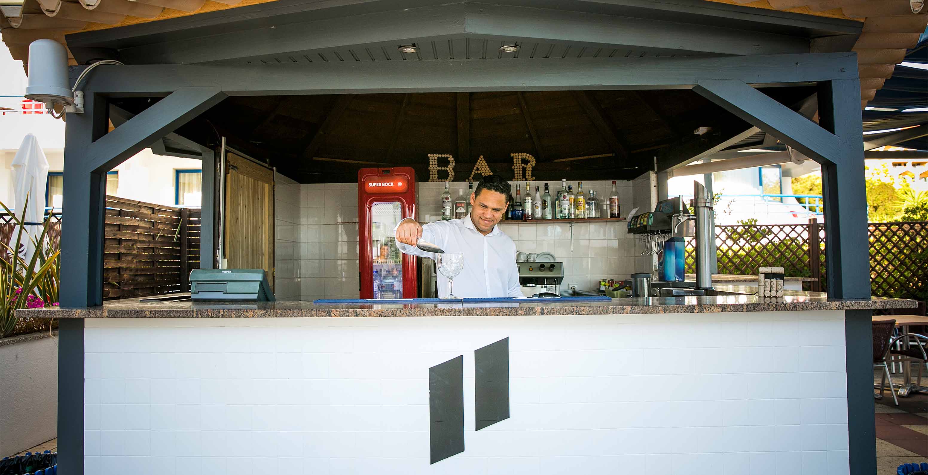 Blick auf die Poolbar mit einem Mitarbeiter, der einen Cocktail zubereitet