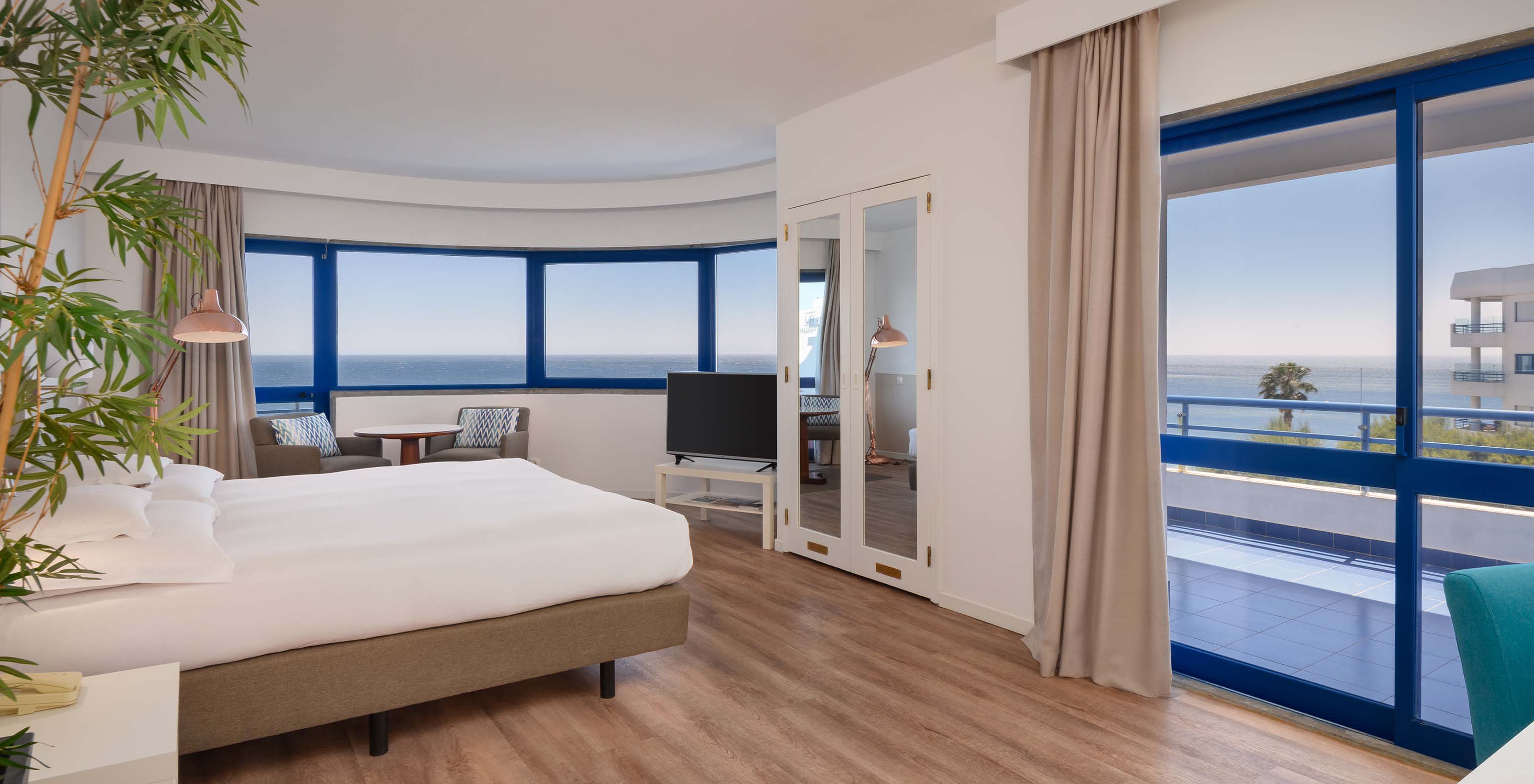 Das Deluxe Superior-Zimmer mit Meerblick im Pestana Cascais hat ein Doppelbett, TV, Spiegel und Blick auf das Meer