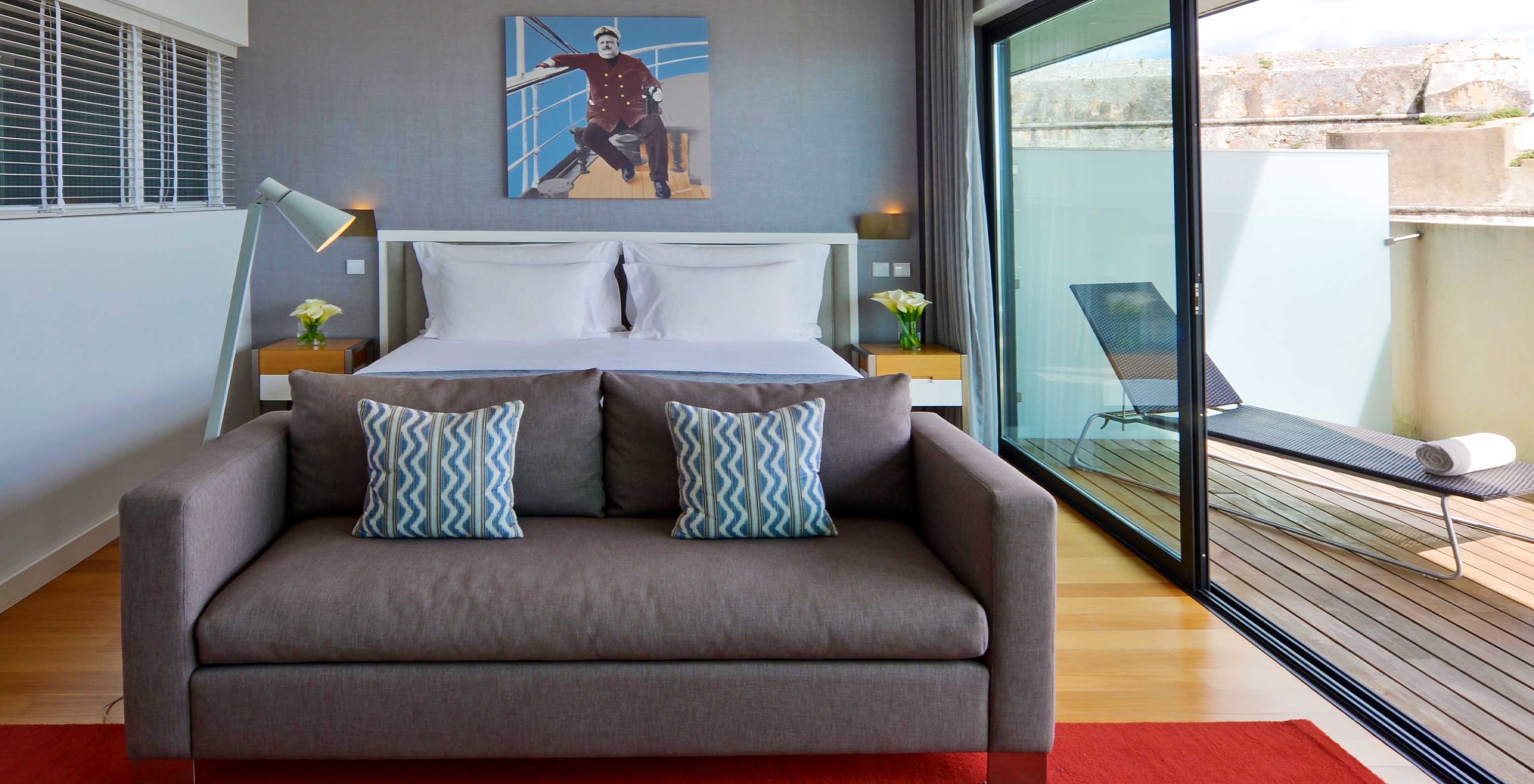 Das Double Superior Zimmer im Pestana Cidadela Cascais hat ein Bild an der Wand, ein Doppelbett und ein bequemes Sofa