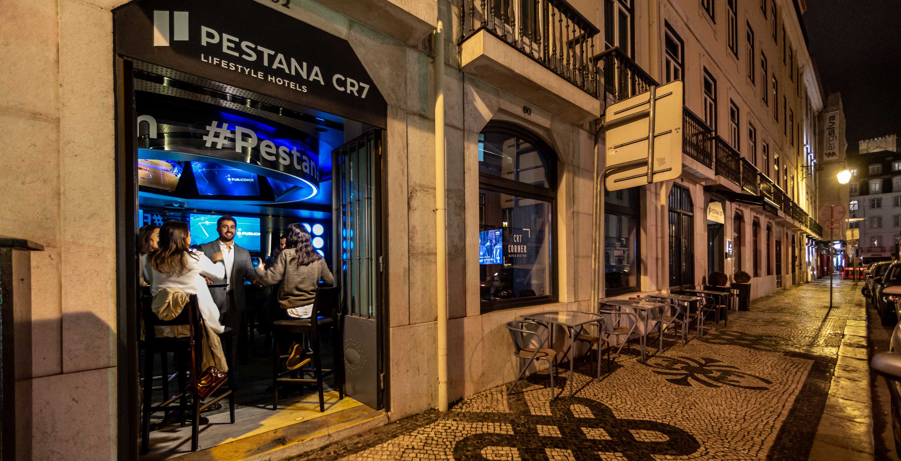 Blick auf die Tür der CR7 Corner Bar, wo eine Gruppe von Freunden an einem Tisch im Inneren sitzt