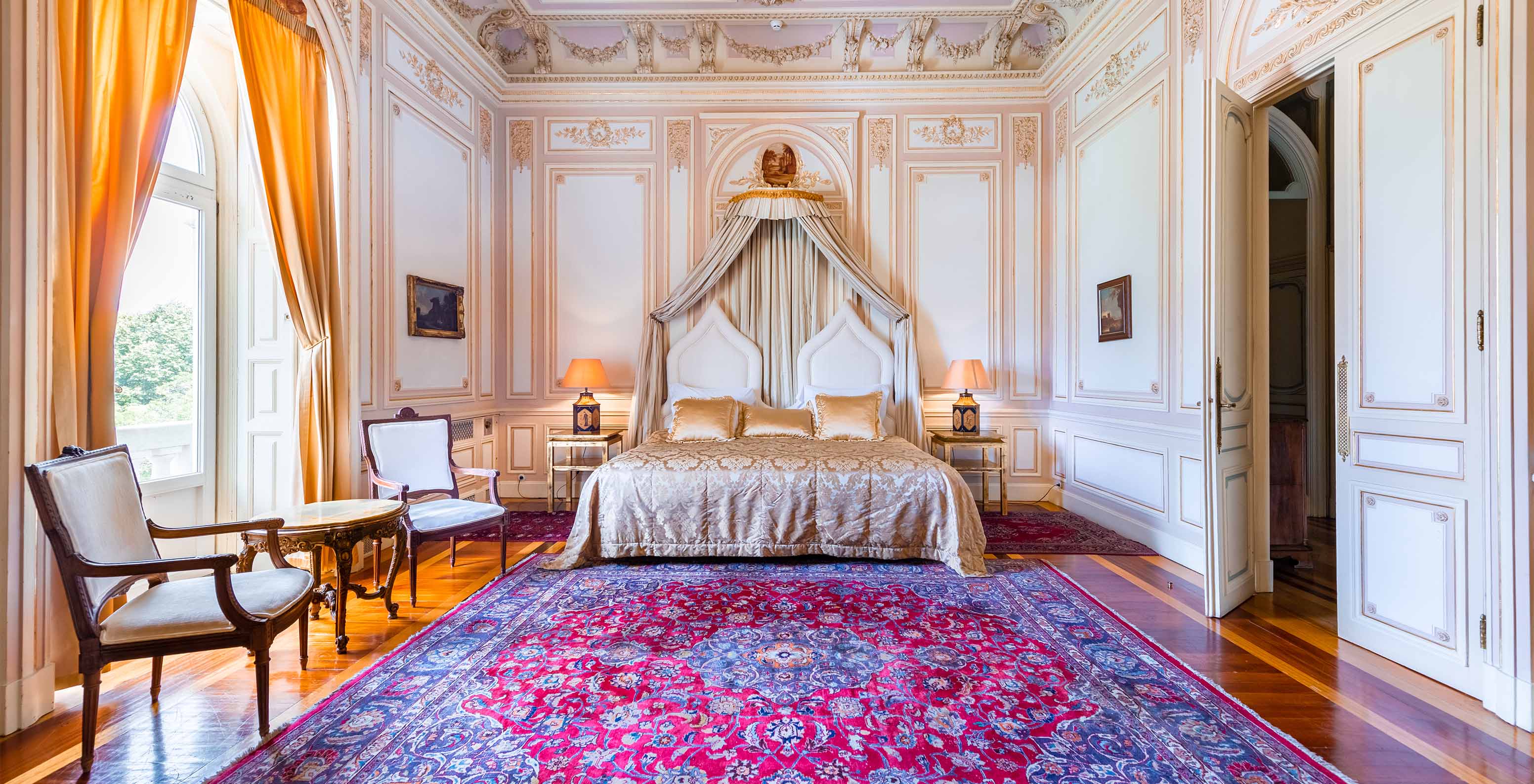 Die D. Carlos Suite im Pestana Palace Lisboa hat ein luxuriöses Zimmer mit Doppelbett und verzierten Decken