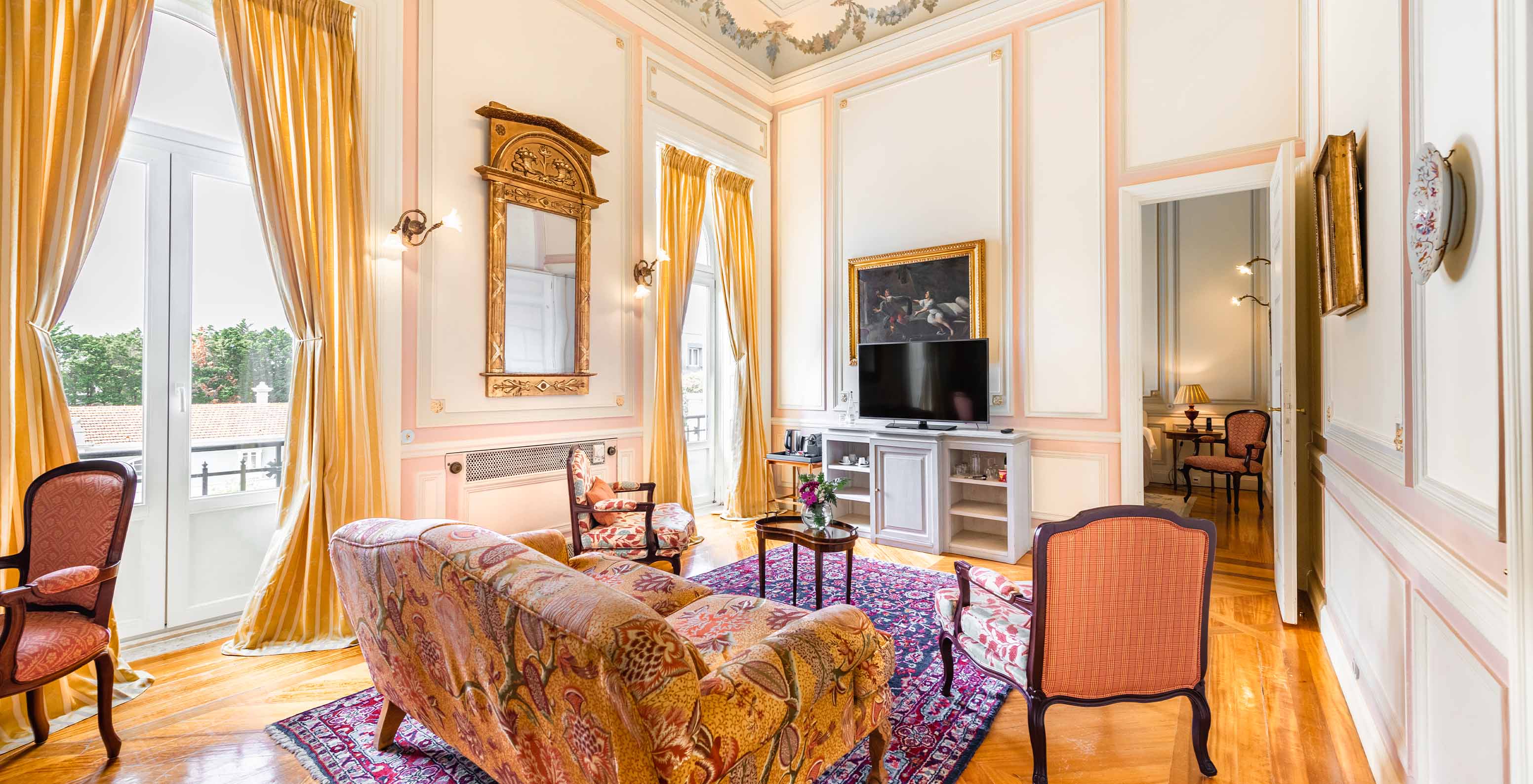 Die D. Amélia Suite im Pestana Palace Lisboa hat ein Wohnzimmer mit Sofa, Fernseher und zwei große Fenster