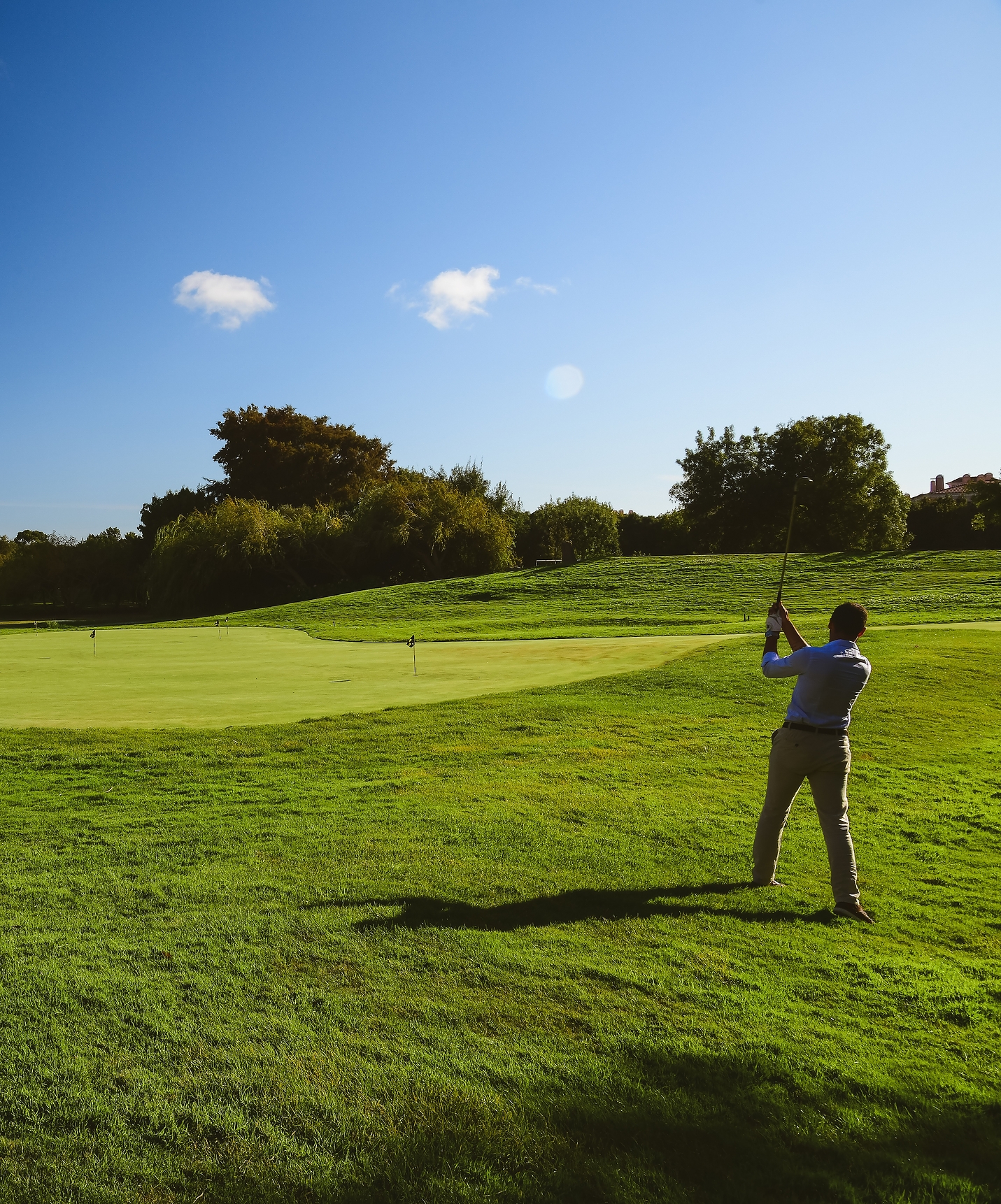 Mann schlägt einen Ball auf dem Golfplatz an einem sonnigen Tag mit blauem Himmel im Pestana Sintra Golf