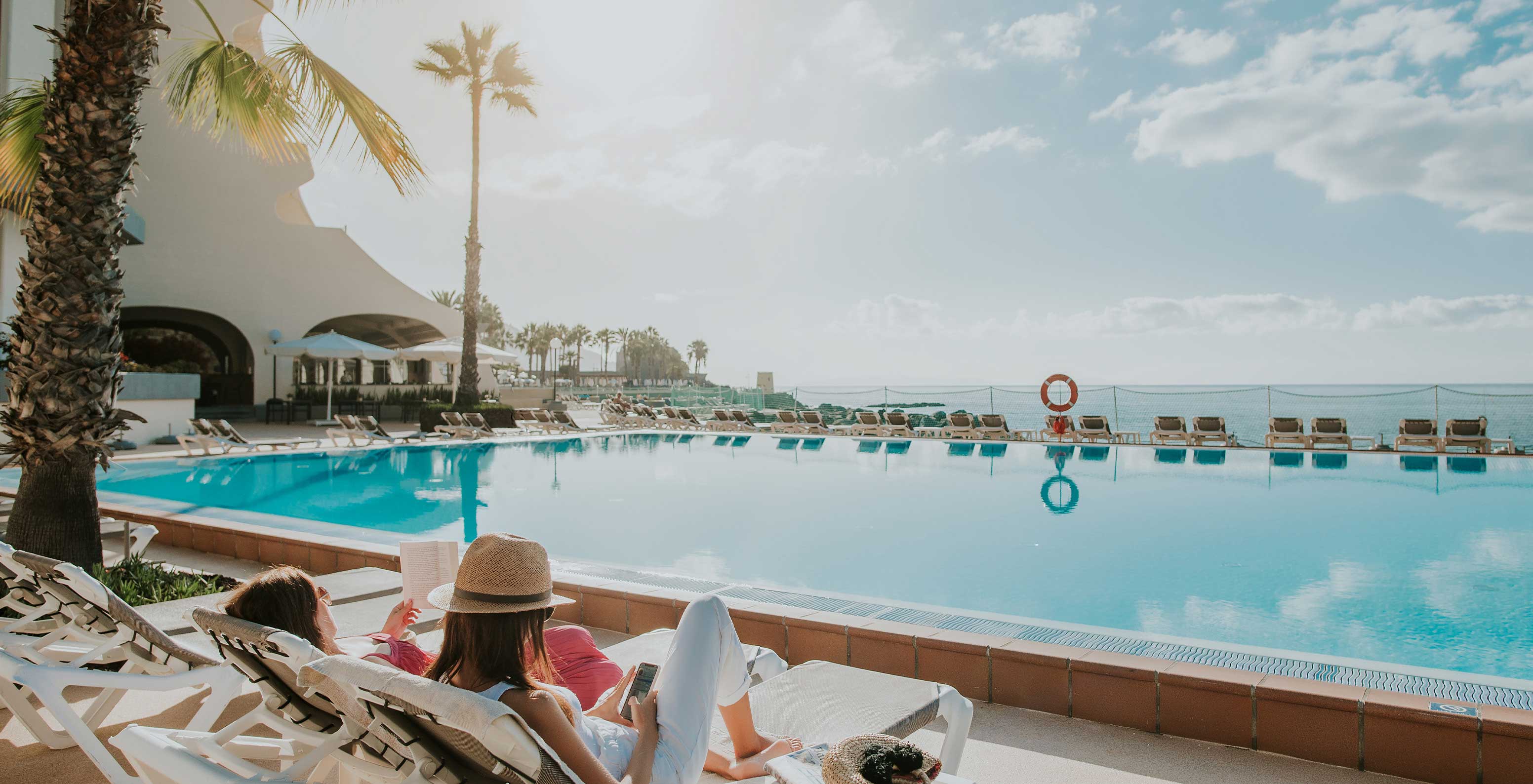 Das Pestana Carlton Madeira, ein Hotel im Zentrum von Funchal am Meer, hat ein Außenschwimmbad mit Liegen