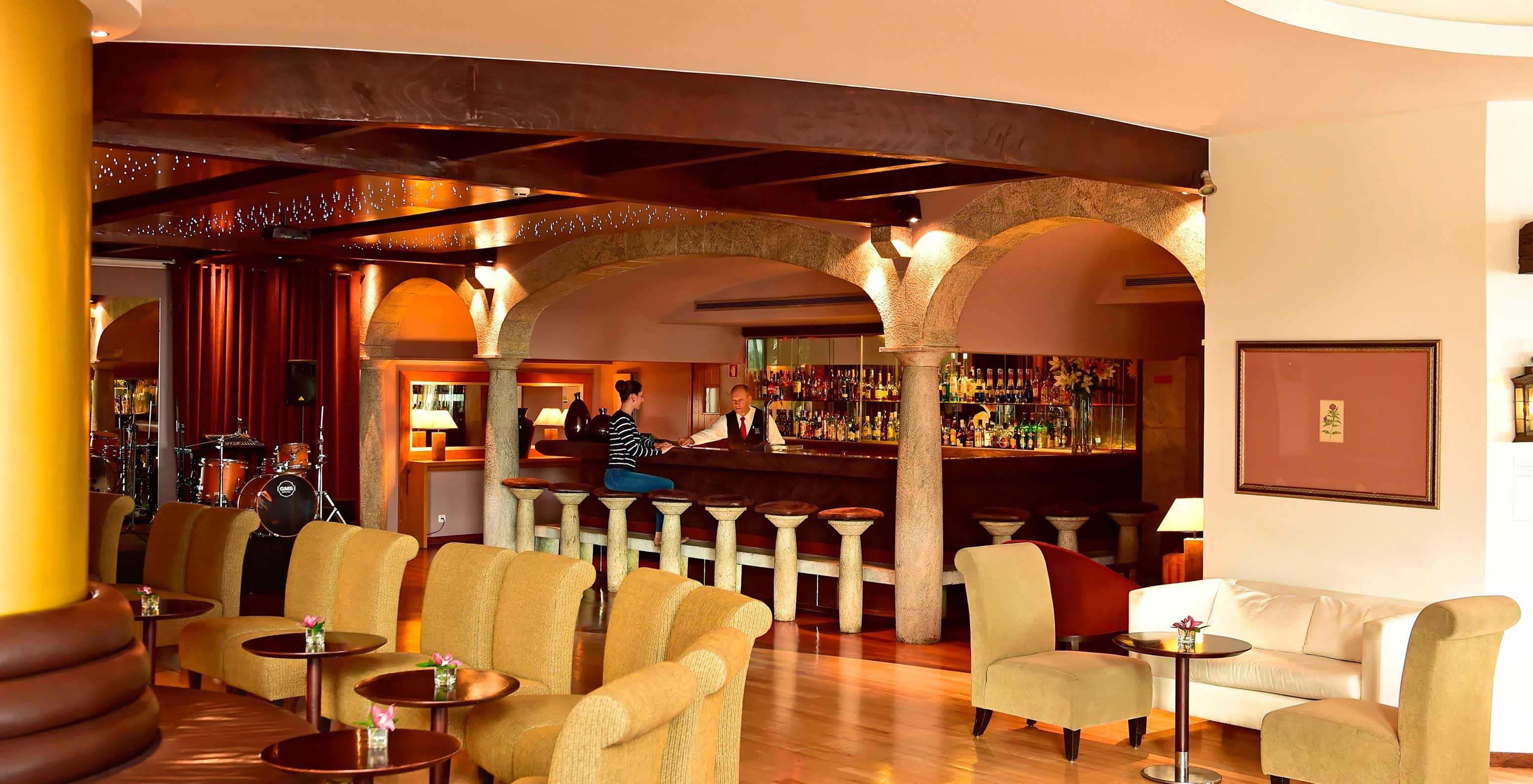 Die Bar Taverna, im 5-Sterne-Hotel in Madeira, hat einen Mann, der Getränke serviert, und mehrere Bänke und Sofas