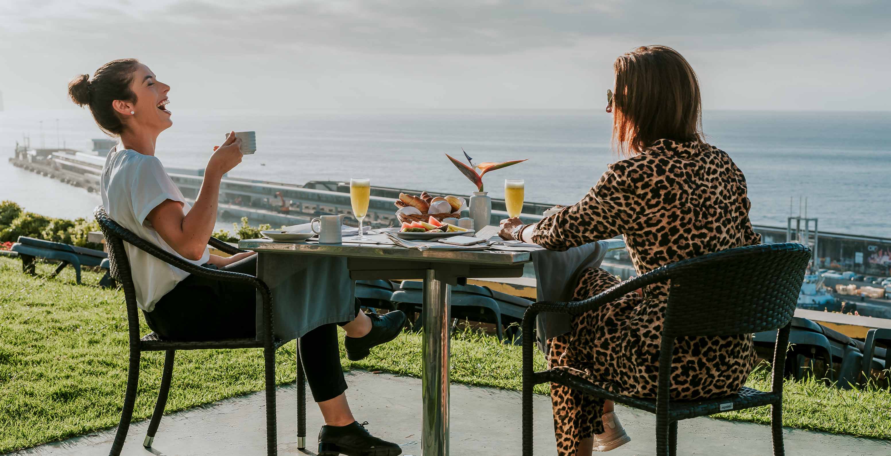 Zwei Freundinnen, die im Freien frühstücken im Hotel in Funchal mit Blick auf das Meer, mit Spa und Pool