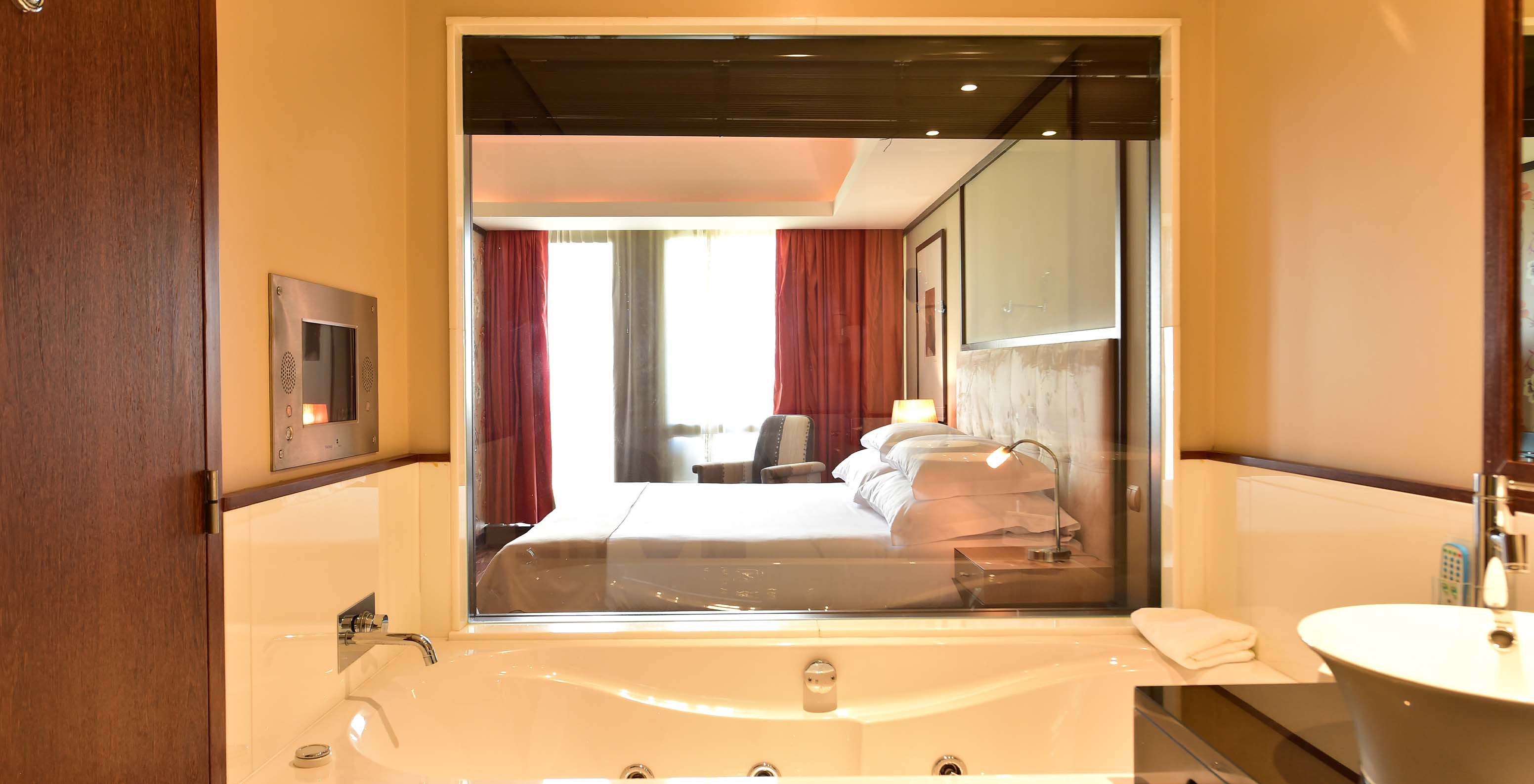 Die Präsidentensuite im Pestana Casino Park hat ein Badezimmer mit Badewanne mit Blick auf das Doppelbett im Zimmer