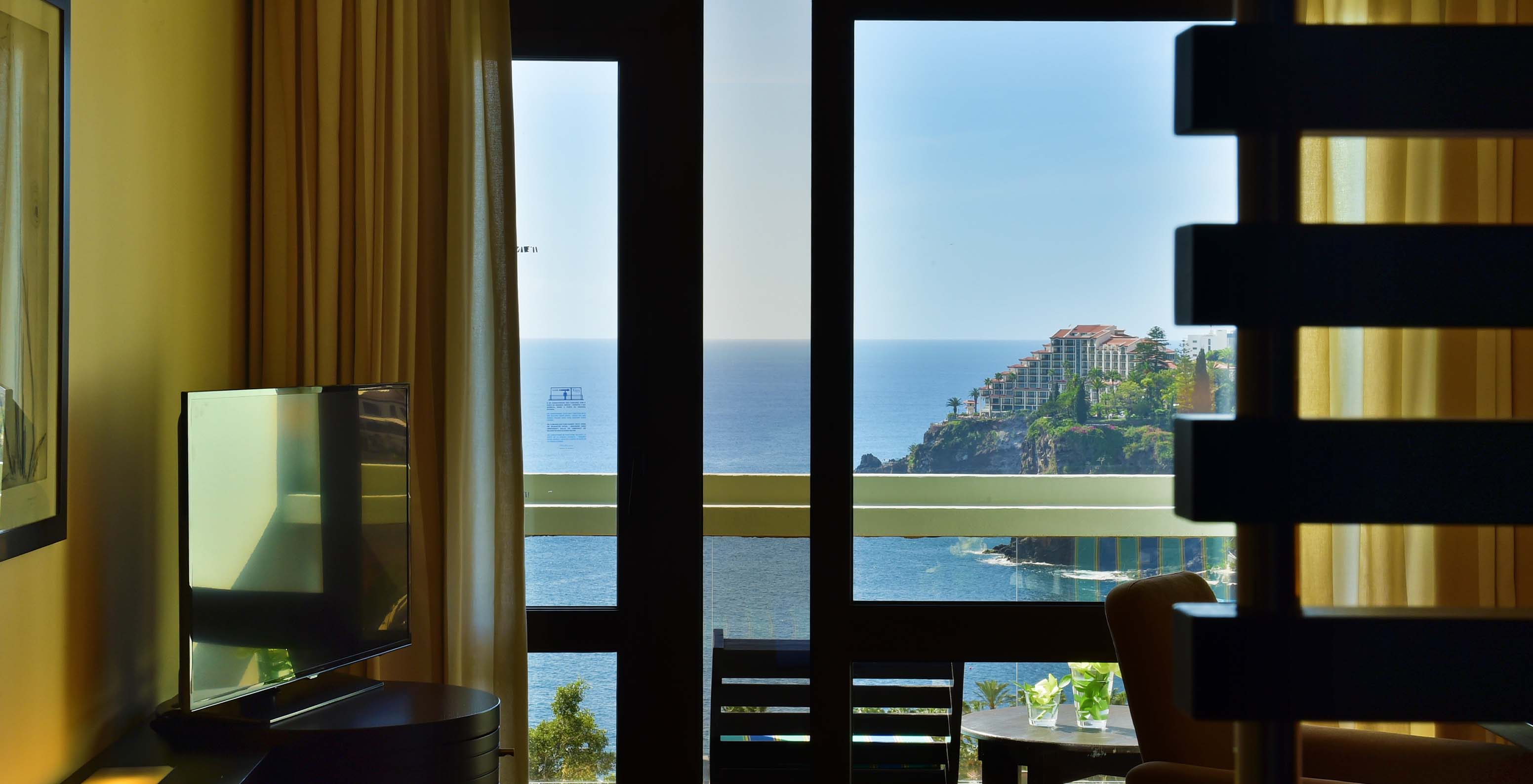 Die Suite mit Blick auf das Land im Pestana Casino Park hat einen TV und einen Balkon mit Tisch und Meerblick