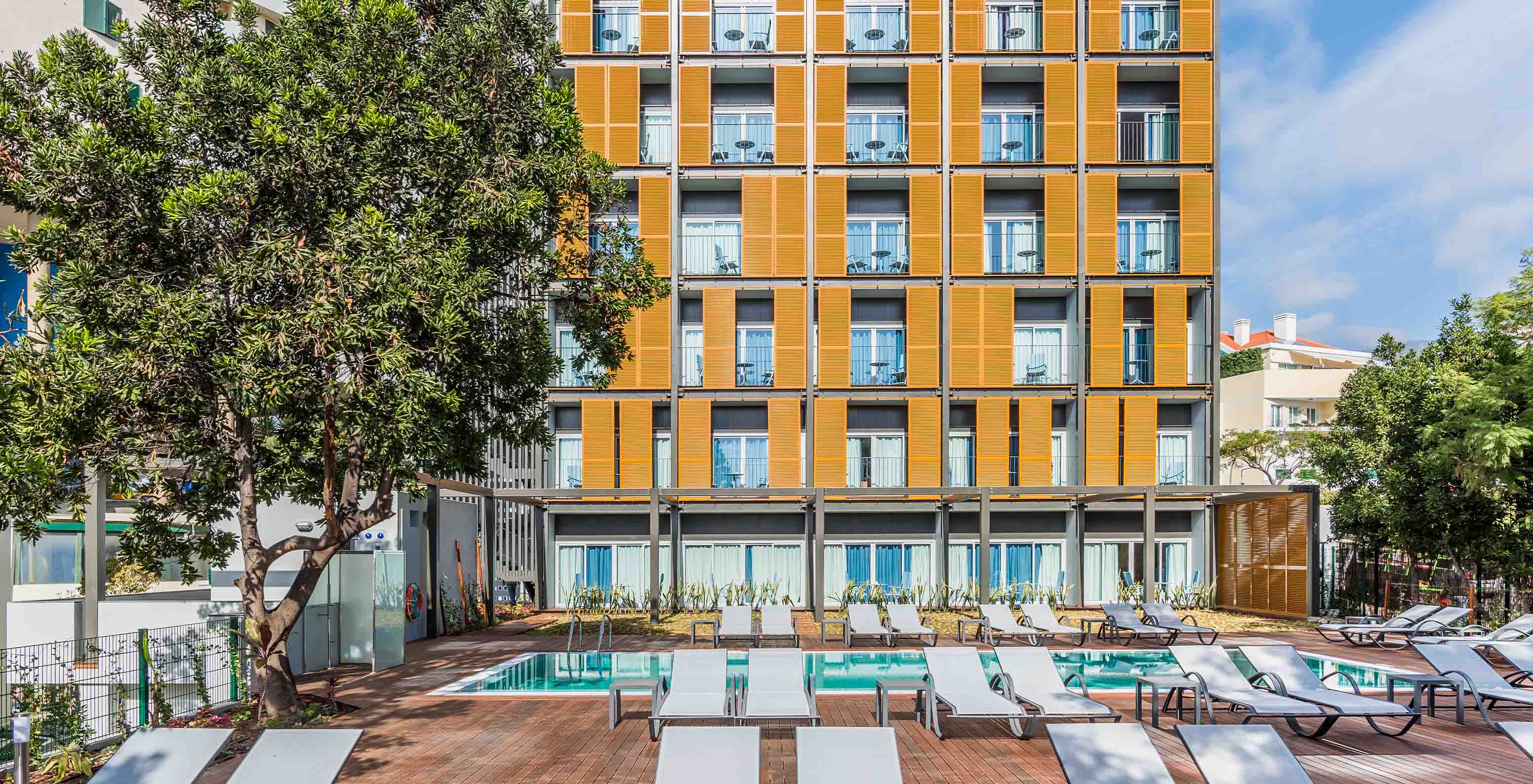 Blick auf die Fassade der Pestana Casino Studios mit Apartments im Stadtzentrum, mit Pool und einem orangefarbenen Gebäude