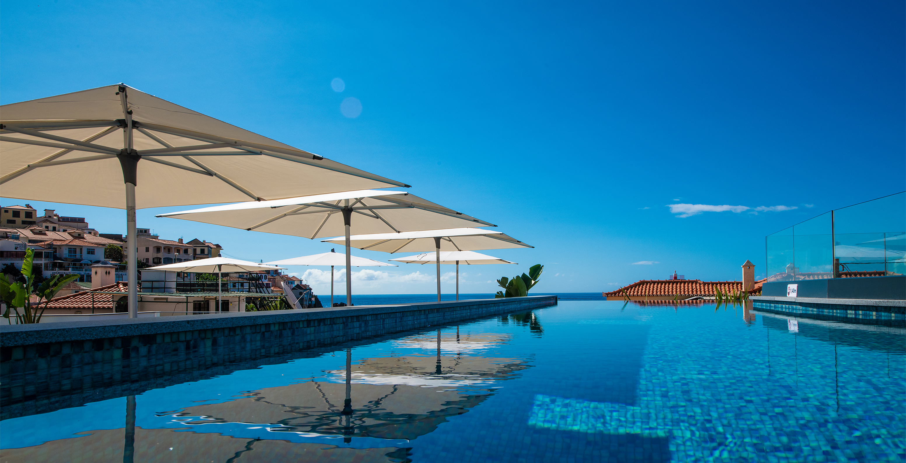 Infinity-Pool des Boutique-Hotels im historischen Zentrum von Câmara de Lobos mit der Stadt und dem Ozean im Hintergrund