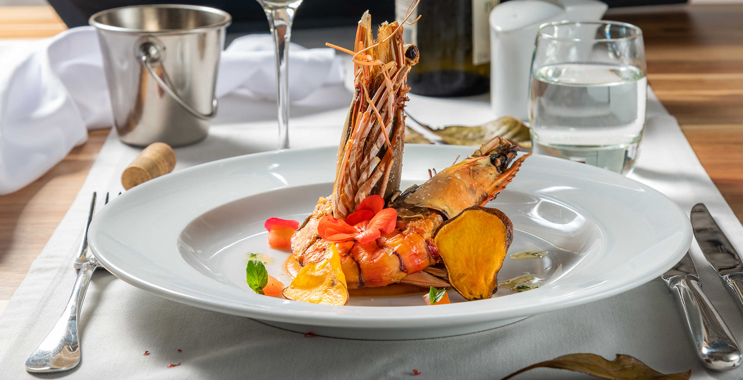 Das Restaurant Pier One Grill, im Hotel in Câmara de Lobos, Madeira, serviert einen Teller mit Garnelen und einem Glas Wein