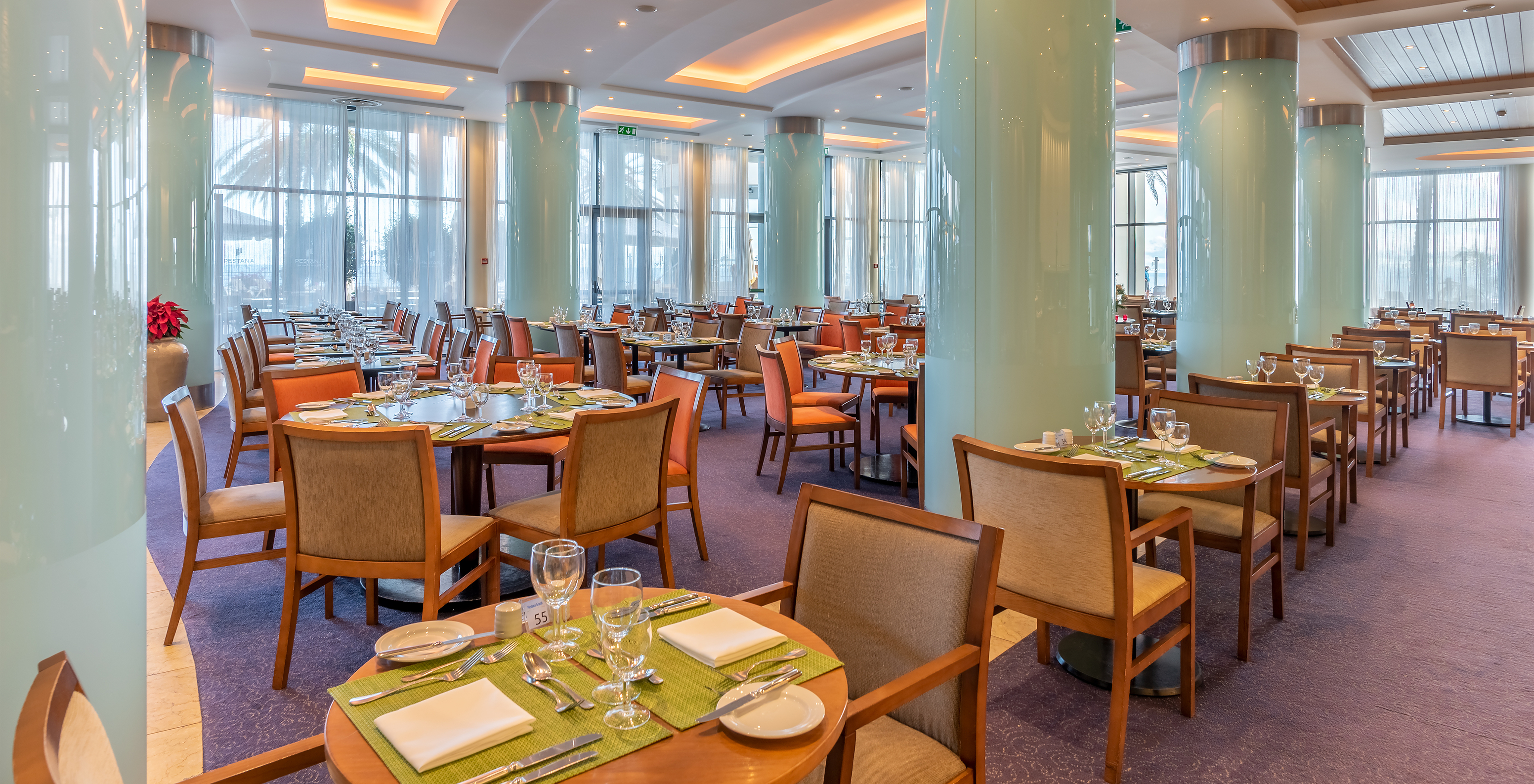 Das Restaurant Atrium, im 5-Sterne-Hotel in Funchal, Madeira, hat einen großen Raum mit blauen Säulen, Tischen und Stühlen