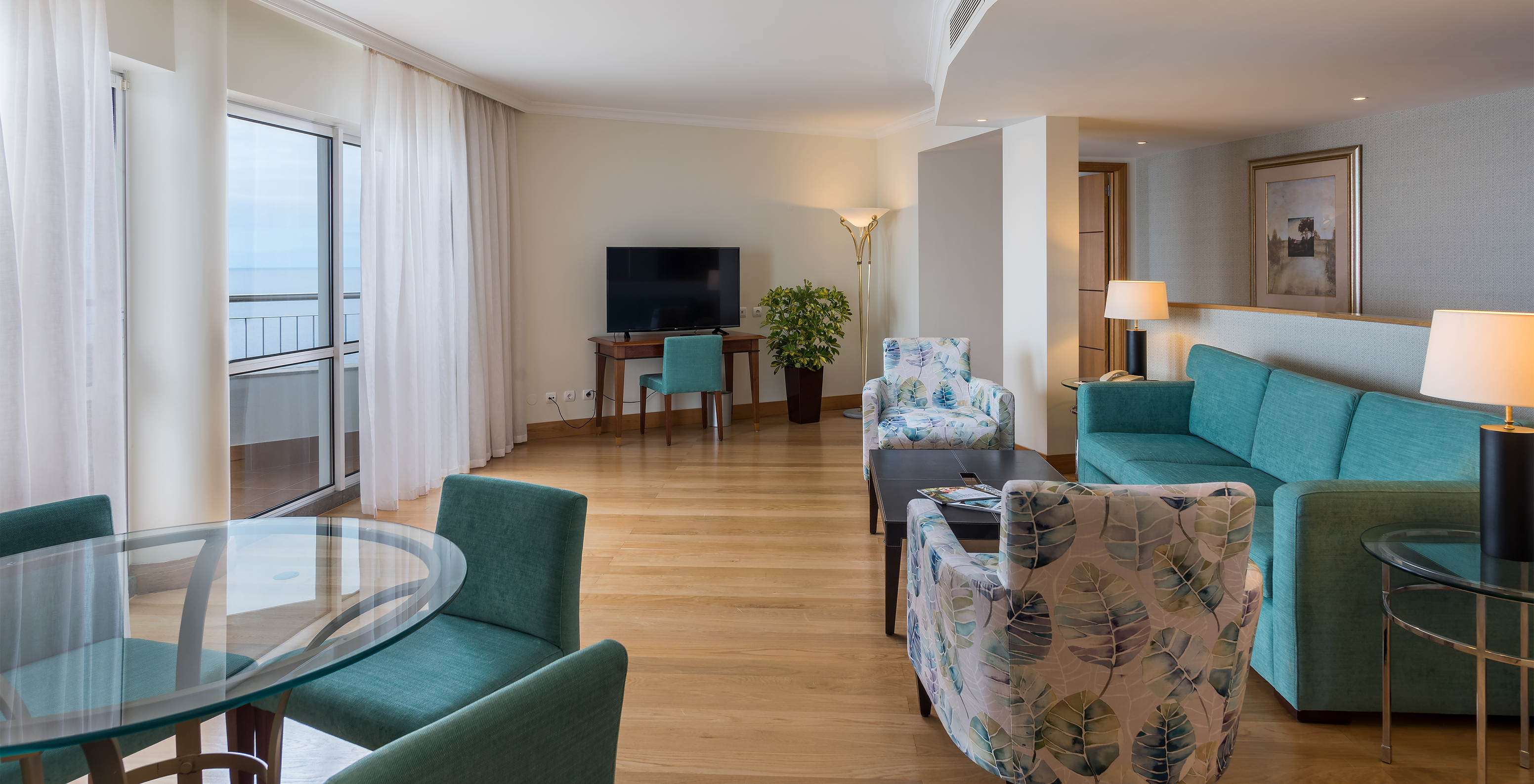 Die Master Suite mit Meerblick im Pestana Grand hat Wohnzimmer, Sofa und Tisch sowie Fernseher