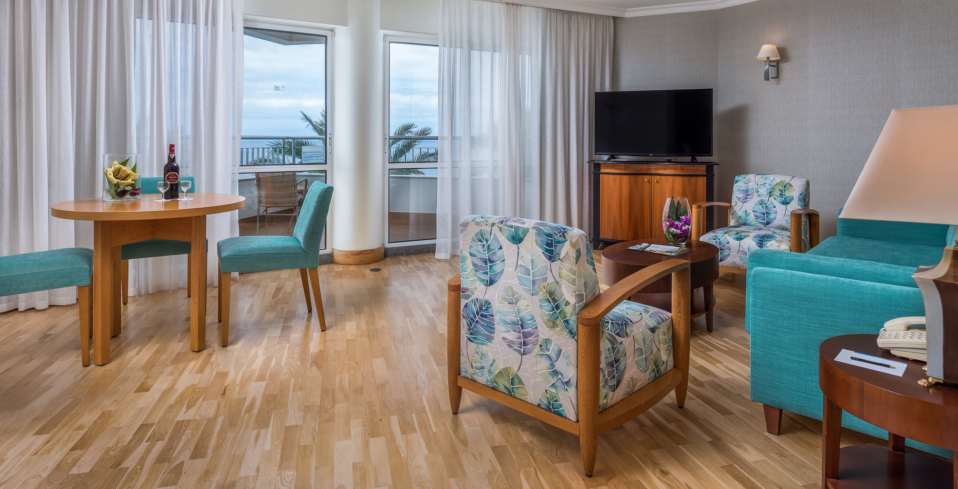 Die Standard Suite mit Meerblick im Pestana Grand hat Wohnzimmer mit kleinem Tisch und Fernseher