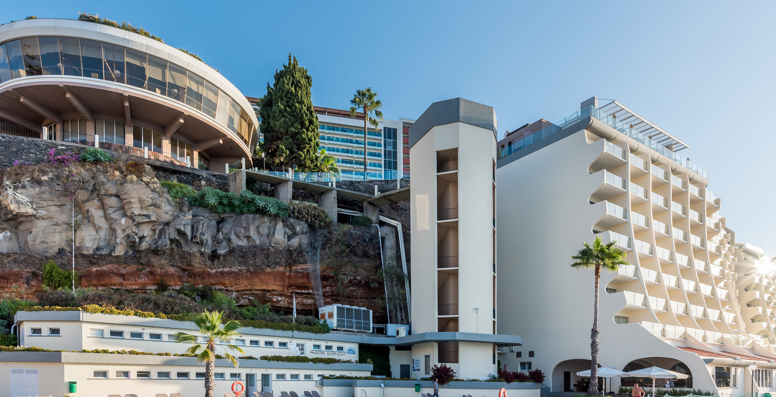 Frau entspannt im Pool des Pestana Madeira Beach Club, mit dem Hotel im Hintergrund