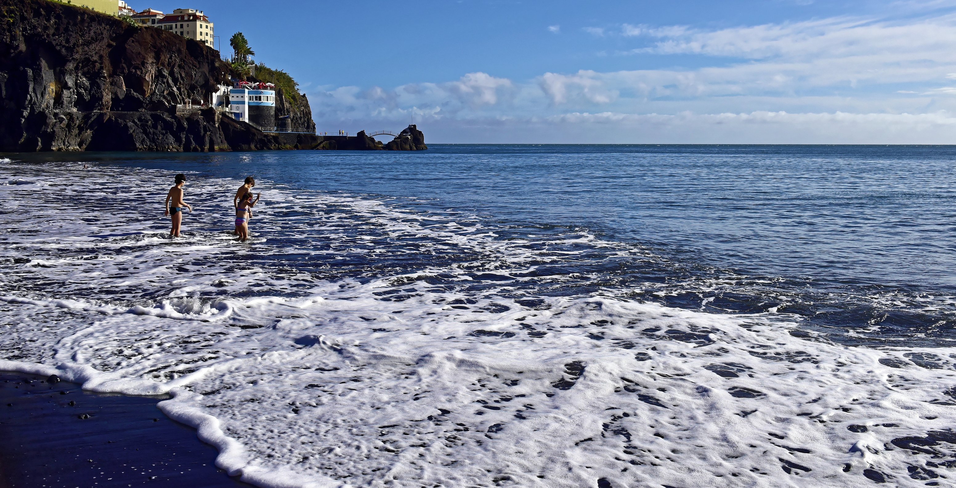 Strand in Madeira, in der Nähe des Pestana Ocean Bay, mit Kindern, die im Wasser spielen