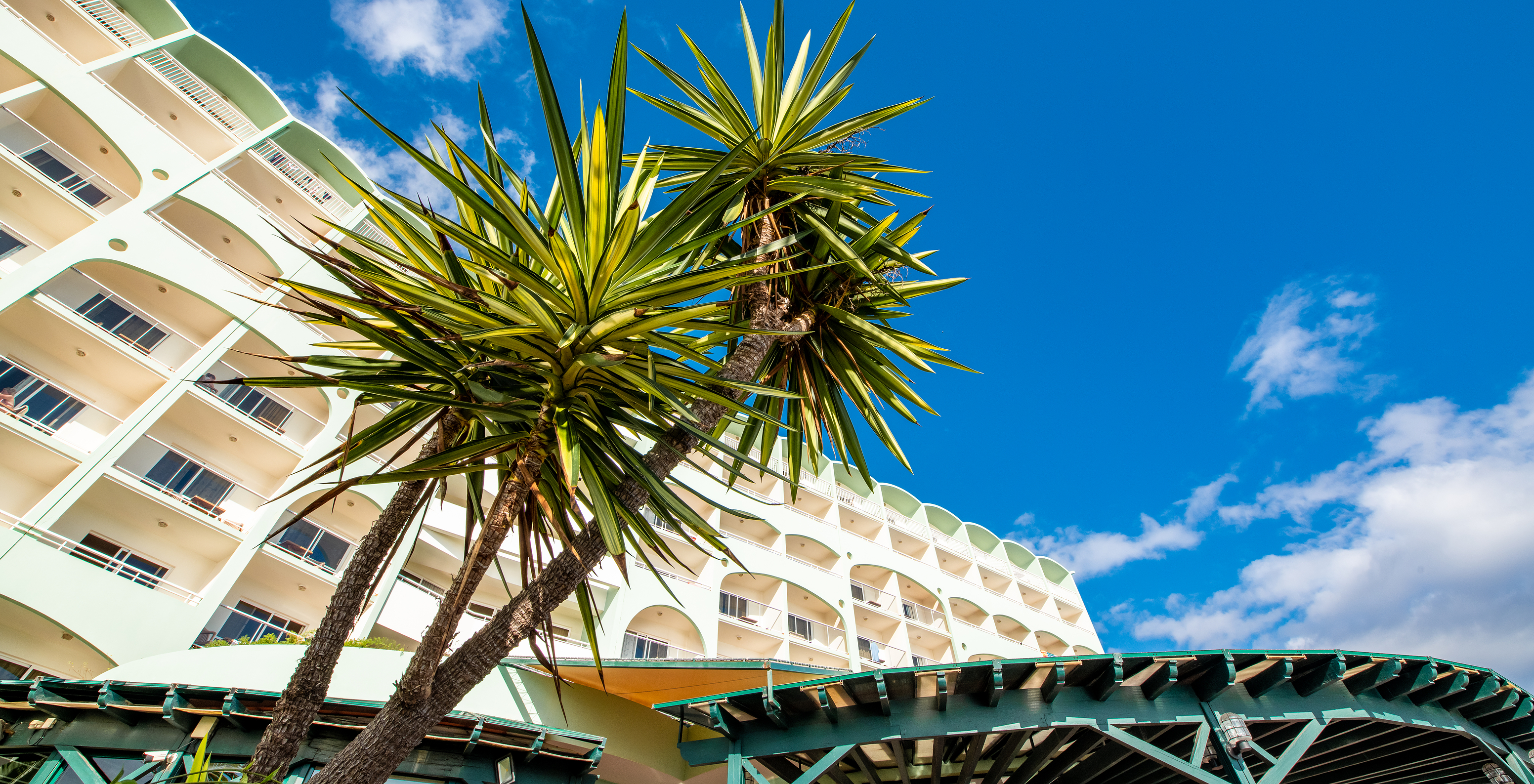 Außenansicht des Pestana Ocean Bay All Inclusive, mit mehreren Balkonen, Palmen und der Markise der Terrasse im Restaurant