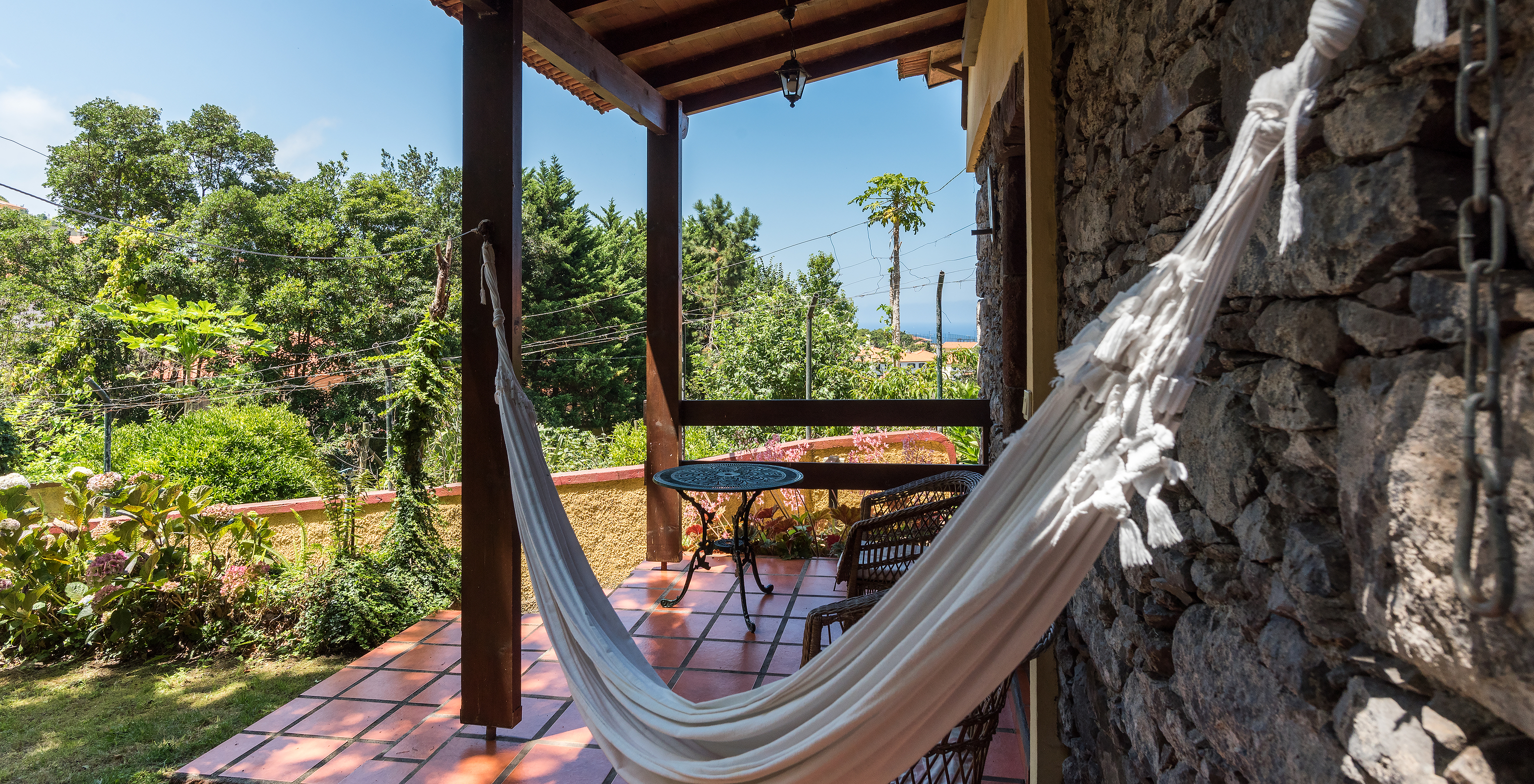 Die Villen des Pestana Quinta do Arco haben eine Hängematte auf der Terrasse, mit Stühlen und Tisch und Blick auf den Garten