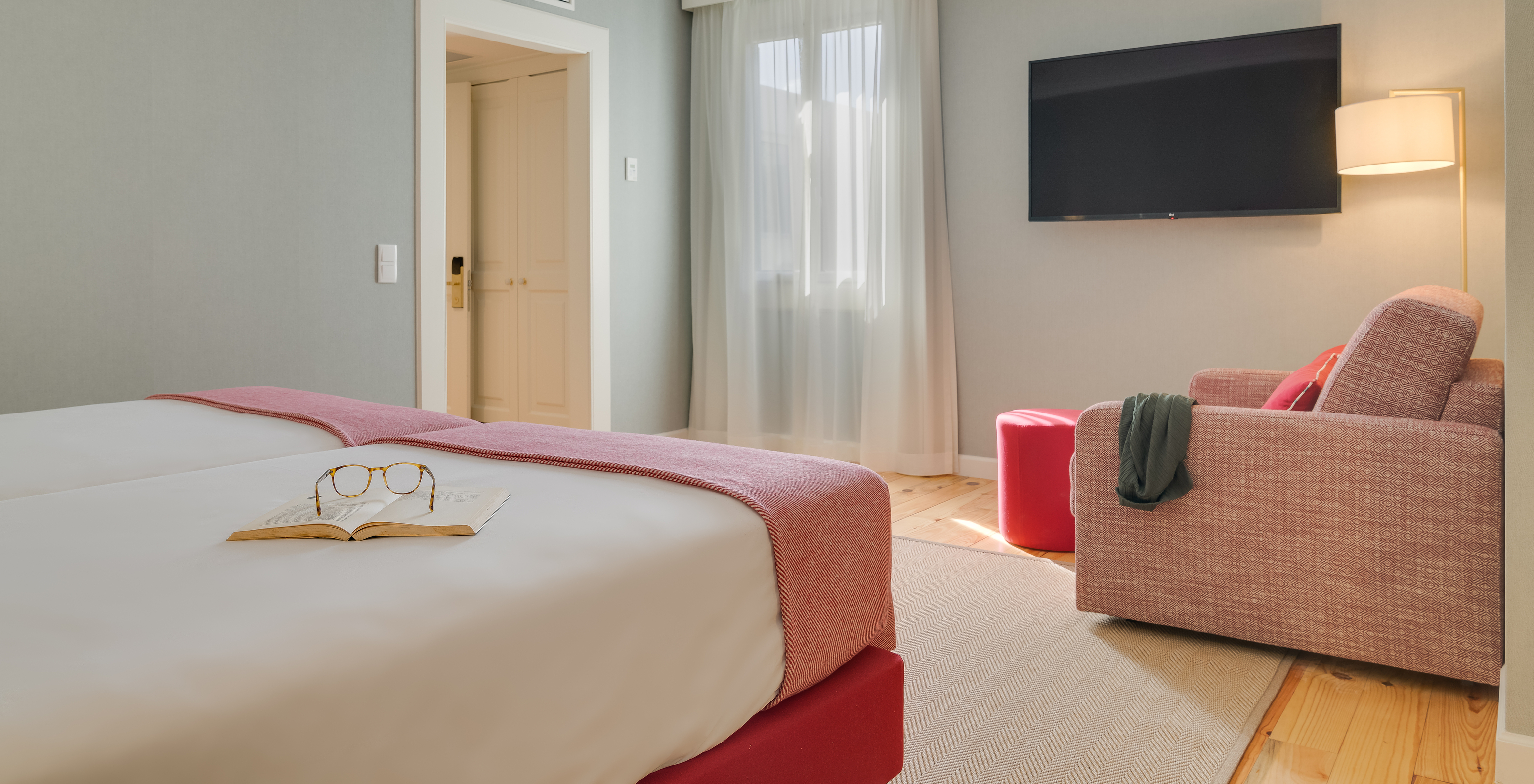 Junior Suite im Pestana Quinta Perestrello hat einen Fernseher vor den Betten und einen Sessel an der Wand