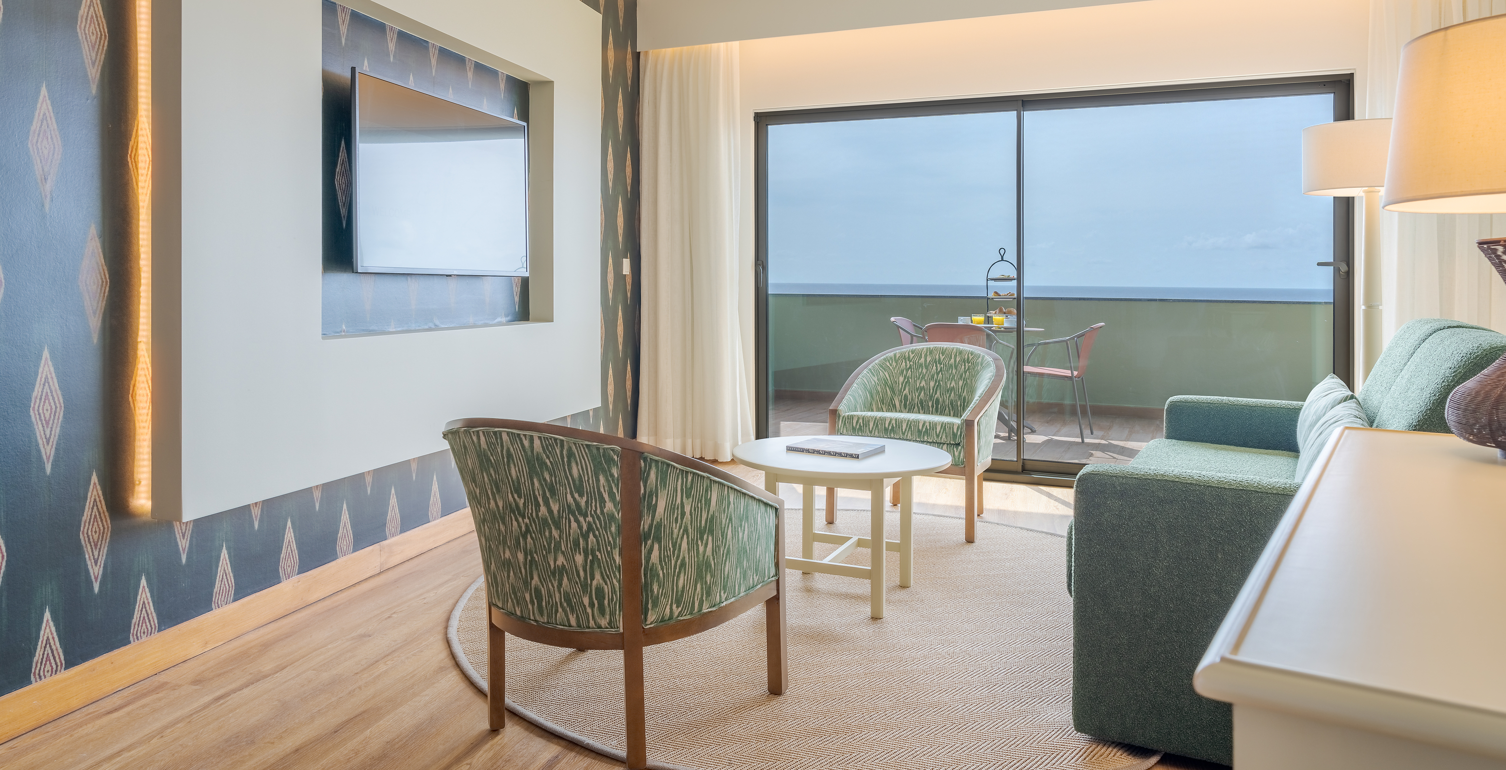 Suite Superior Meerblick Pestana Vila Lido Madeira hat ein Wohnzimmer mit Sofa, Sesseln und Fernseher