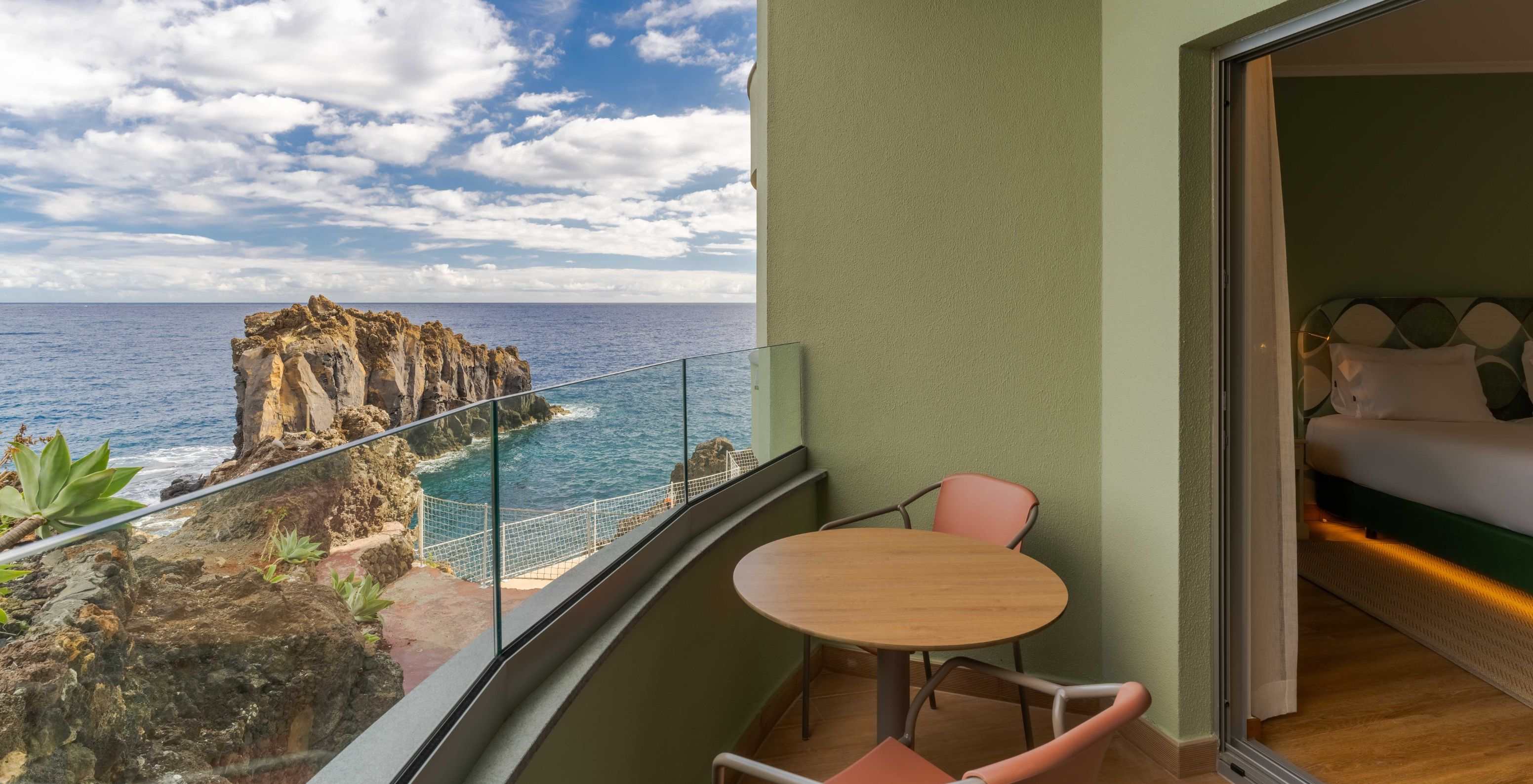 Das Superior seitlicher Meerblick im Pestana Vila Lido Madeira verfügt über einen Balkon mit Tisch und Stühlen.