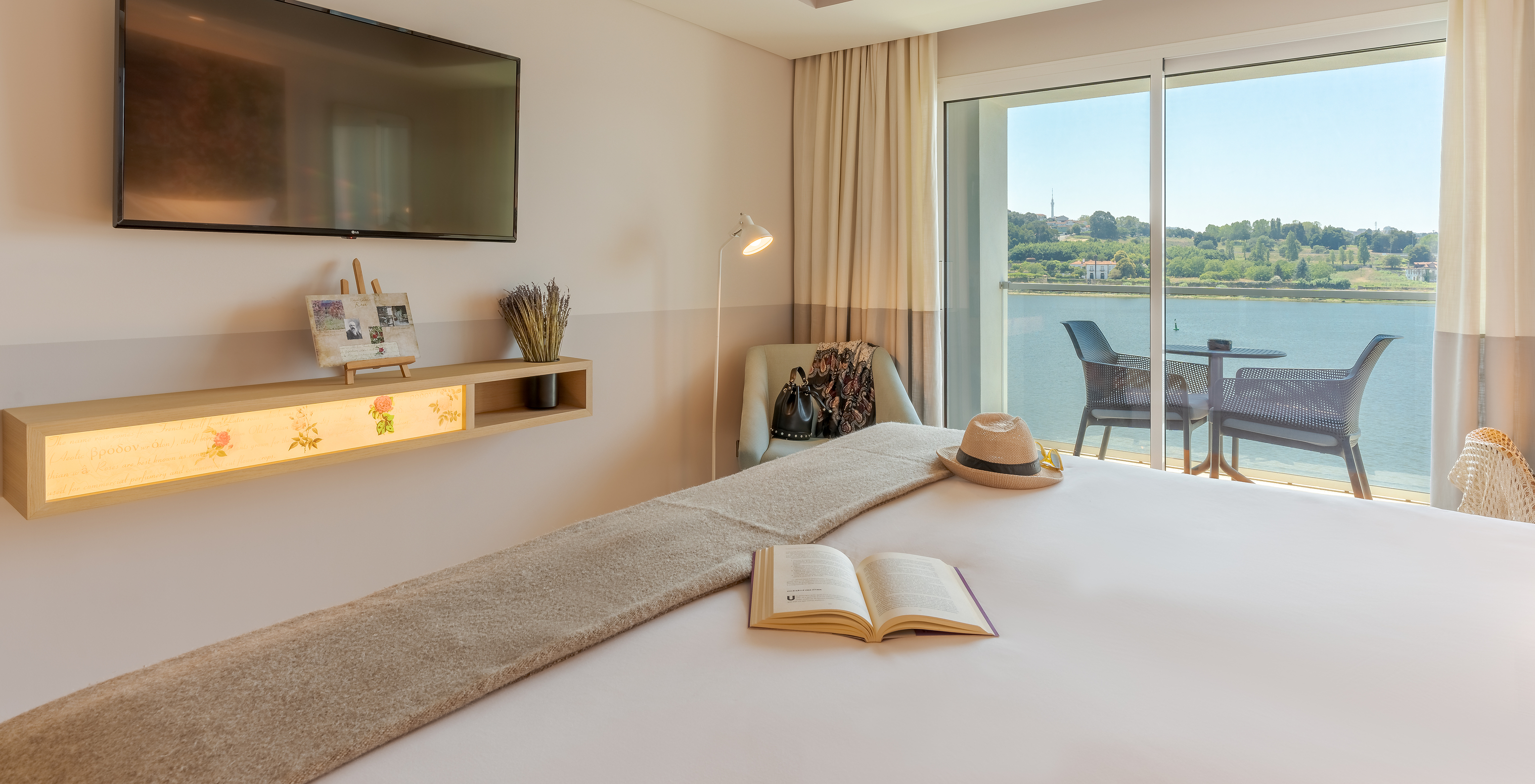 Das Deluxe River View Zimmer im Pestana Douro Riverside hat ein Doppelbett, Fernseher und Sessel